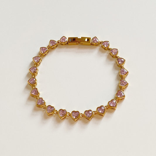 Isolated shot of pink heart tennis bracelet showing secure gold clasp mechanism and stainless steel construction.