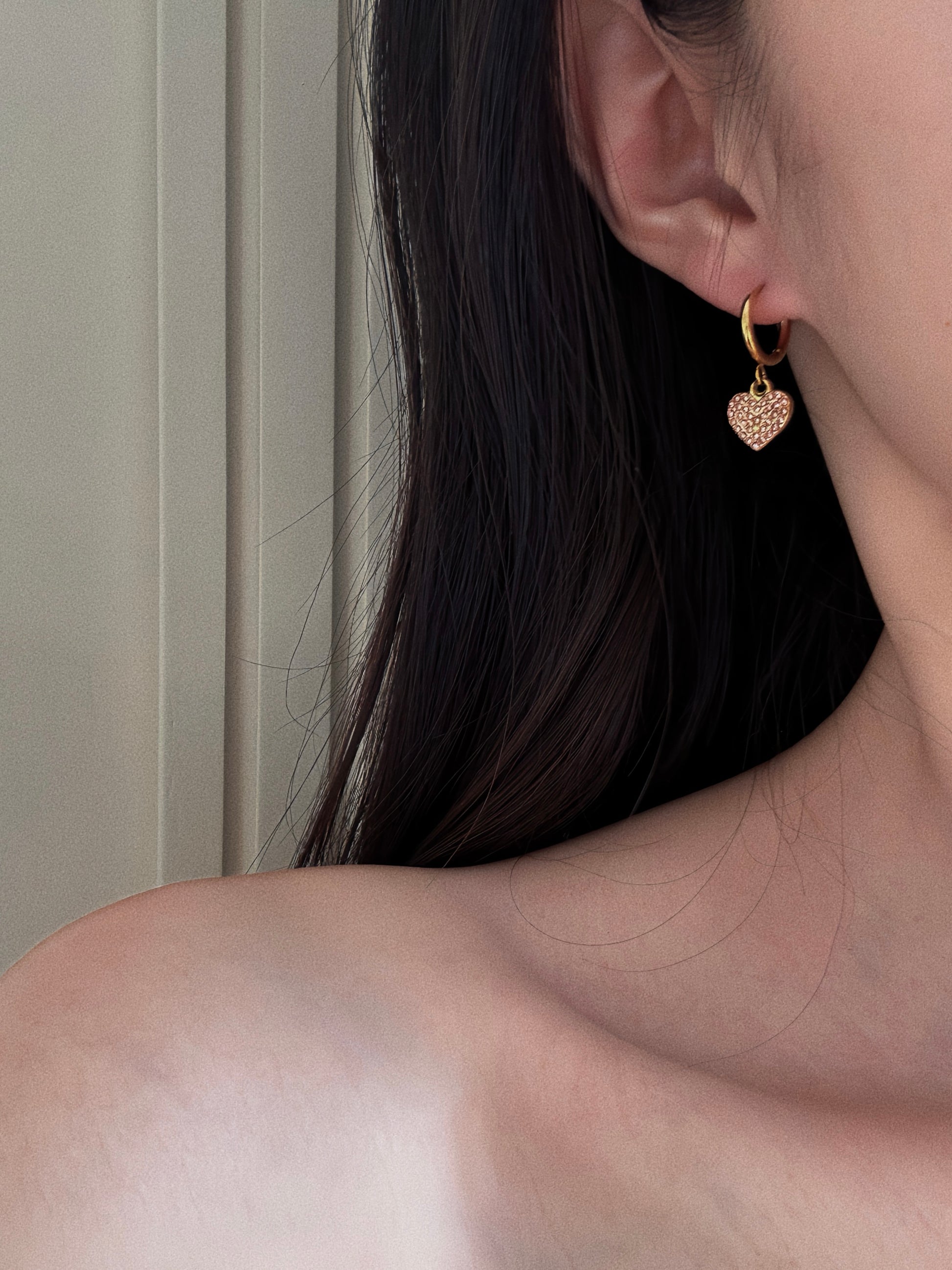 Woman wearing dainty 1cm gold hoop earring with a small pink heart drop, showing size and fit on the earlobe.