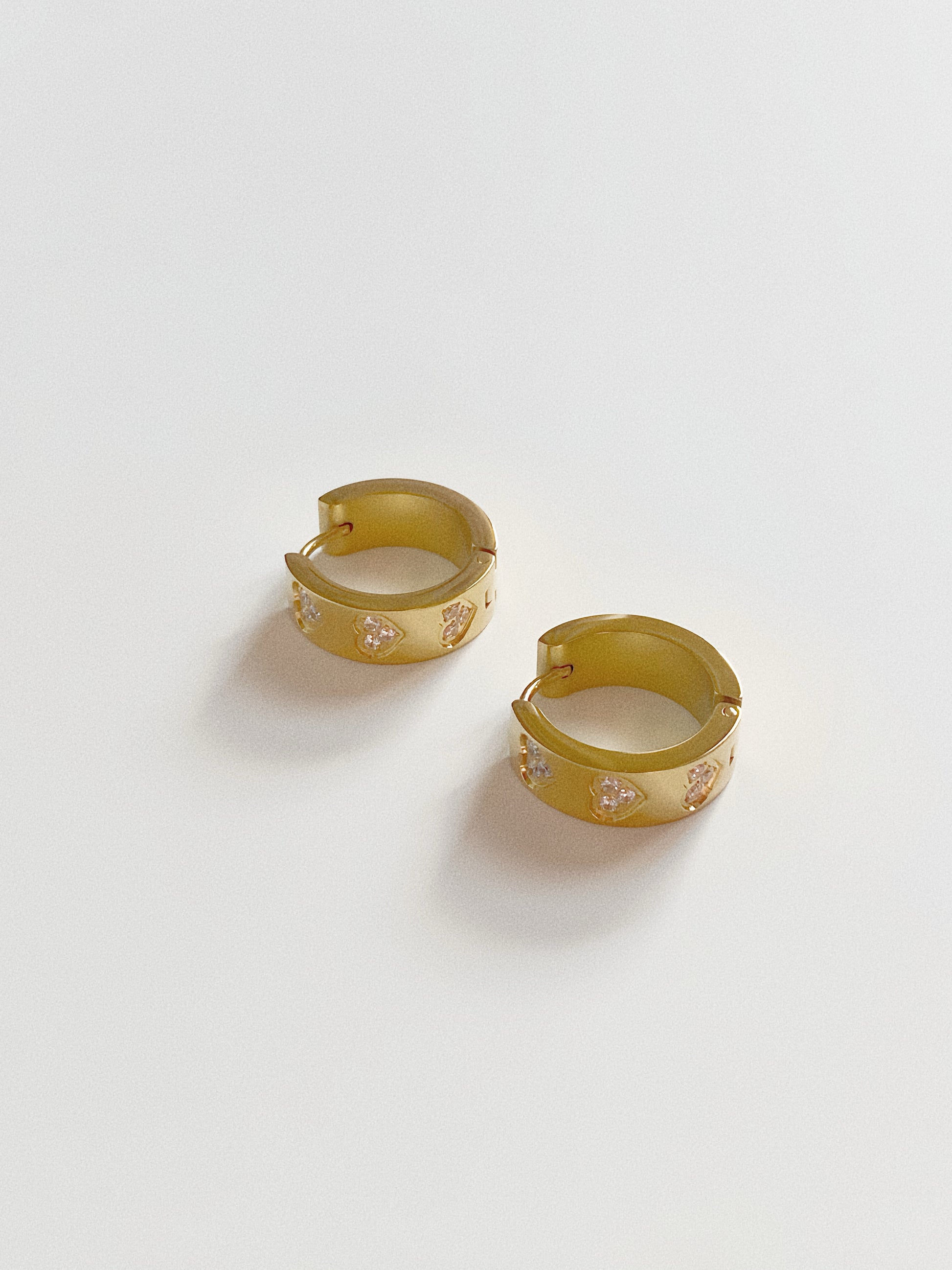 Side view of chunky stainless steel gold hoops, showing the waterproof latch closure and wide profile.