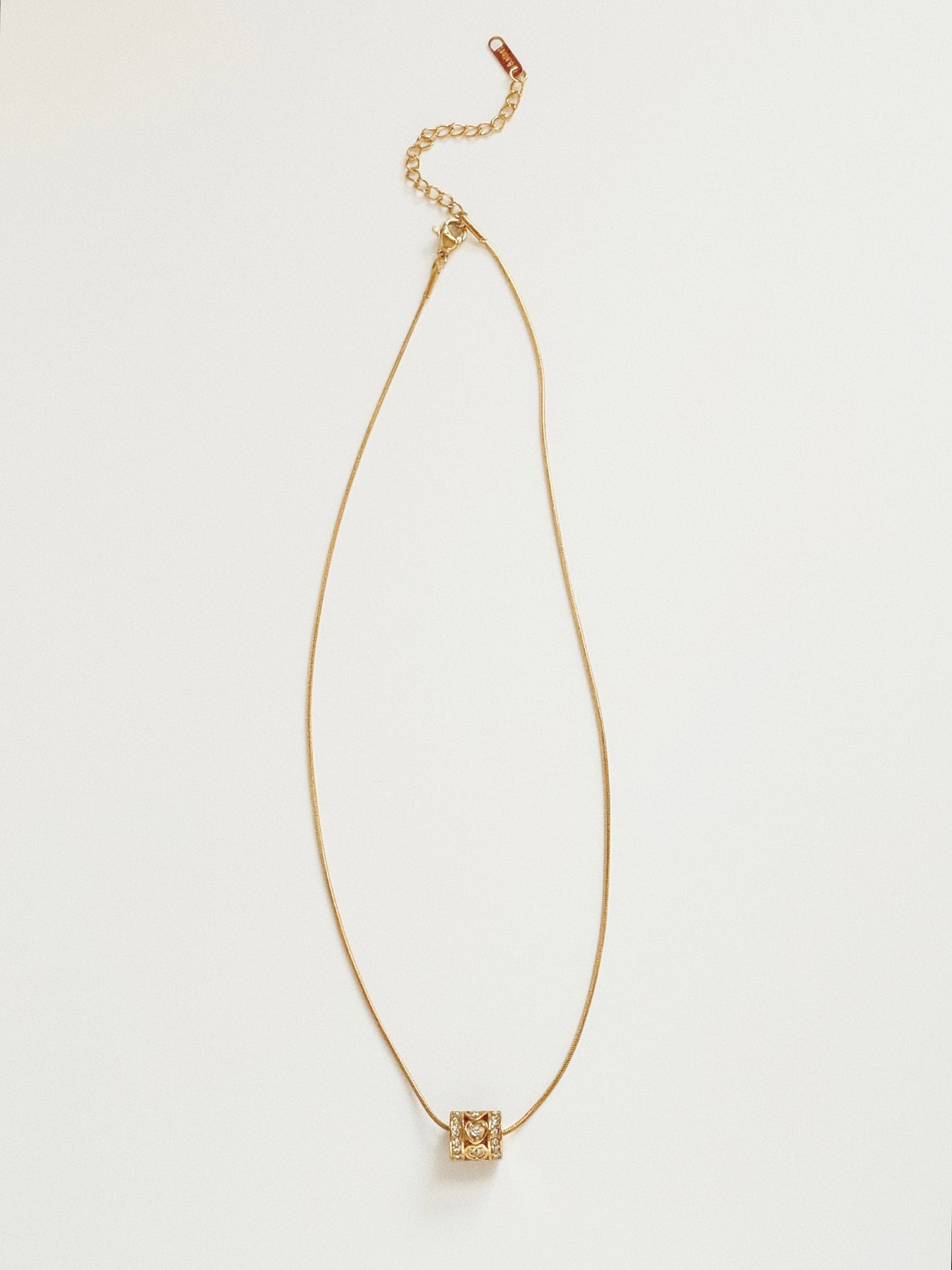 Full length view of waterproof gold snake chain necklace with a sliding heart kaleidoscope pendant.