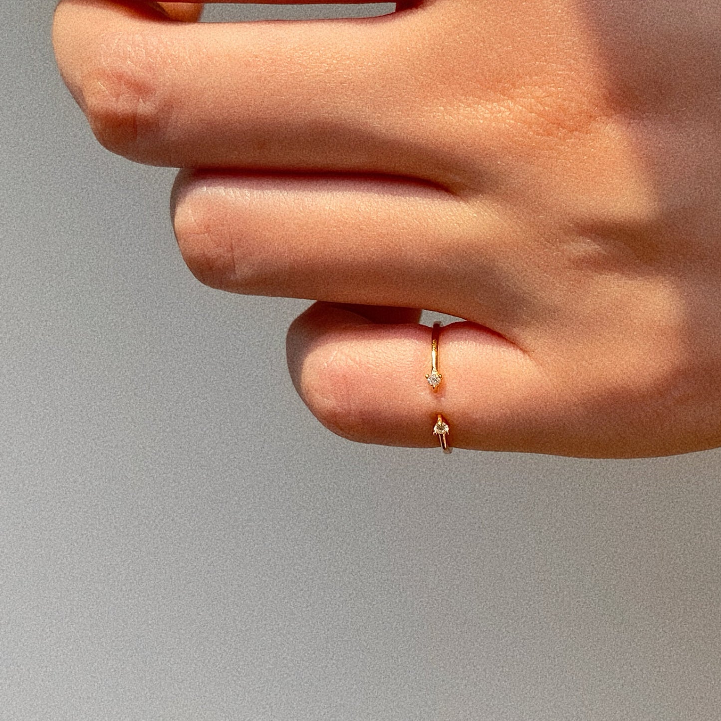 Open gold pinky ring shown on fingertip in natural sunlight