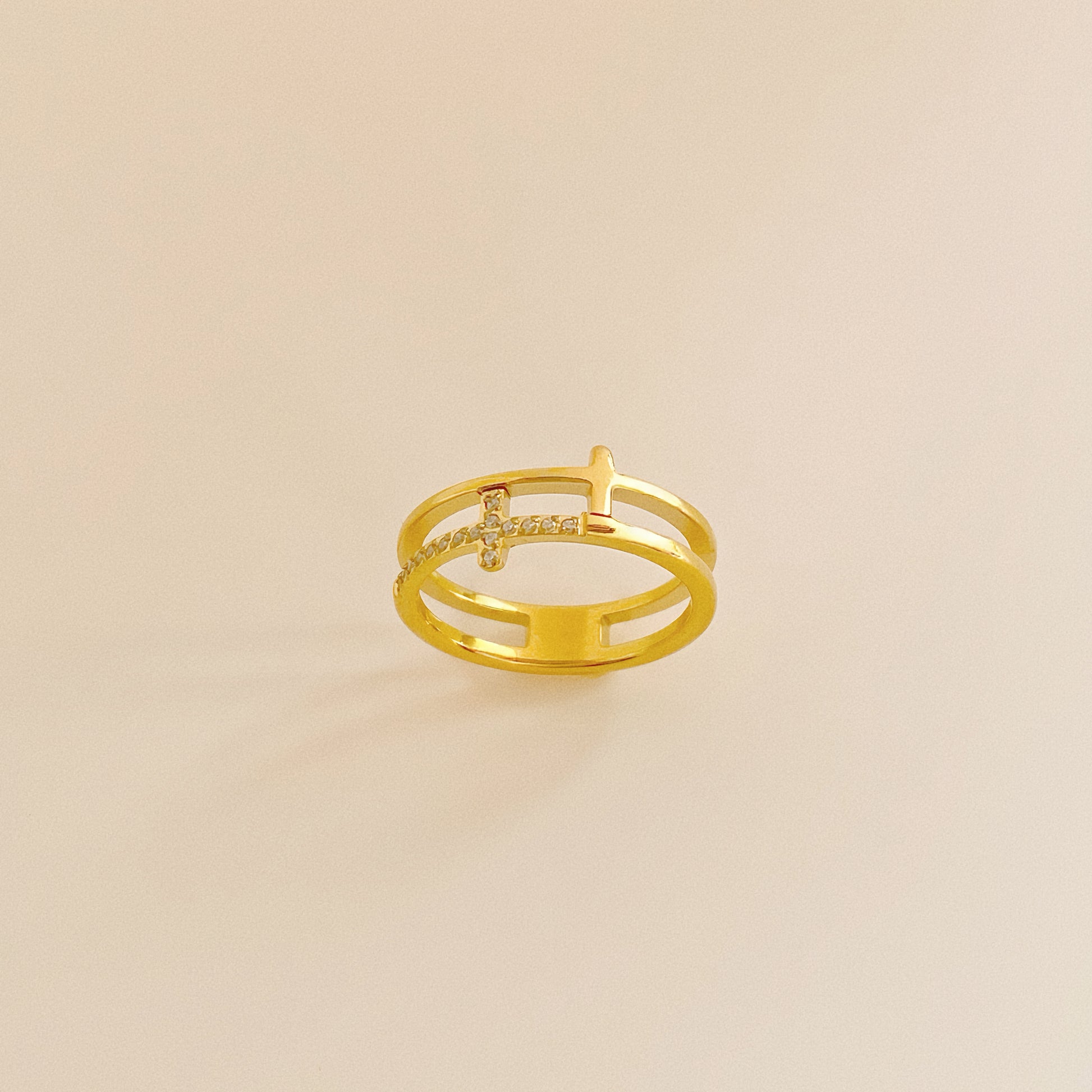 Close up of 18k gold plated stainless steel ring featuring a double band illusion and pave cross.