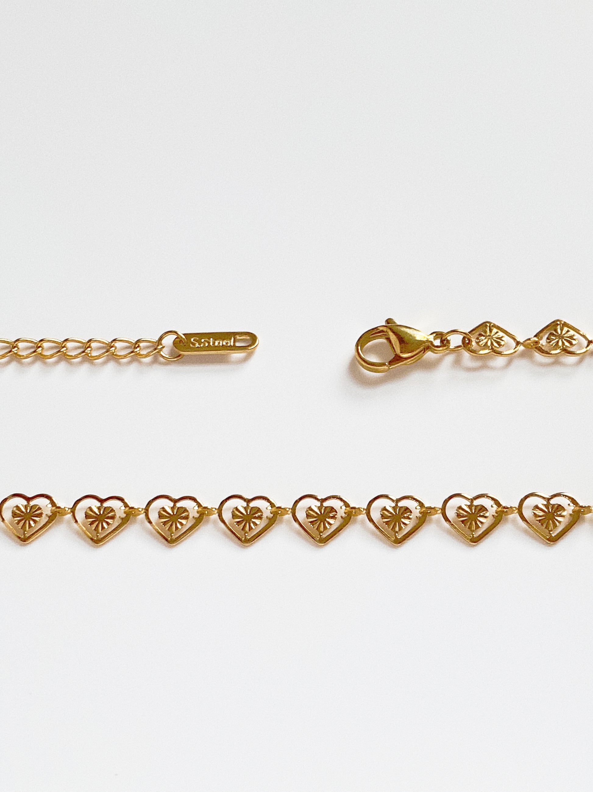 Macro shot highlighting the intricate diamond-cut sunburst texture engraved inside each heart link for maximum sparkle.