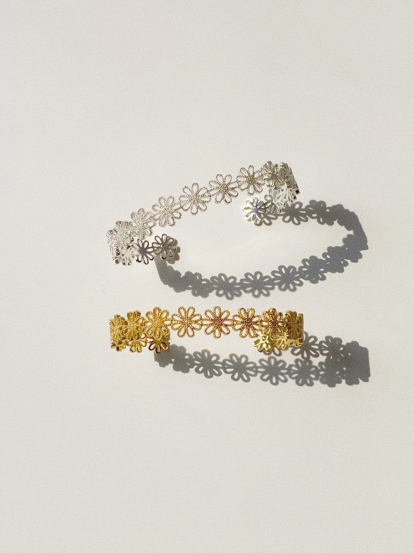 Daisy lace floral open cuff bracelet in gold and silver finishes flat lay with daisy shadow by Deja Vu Jewellery