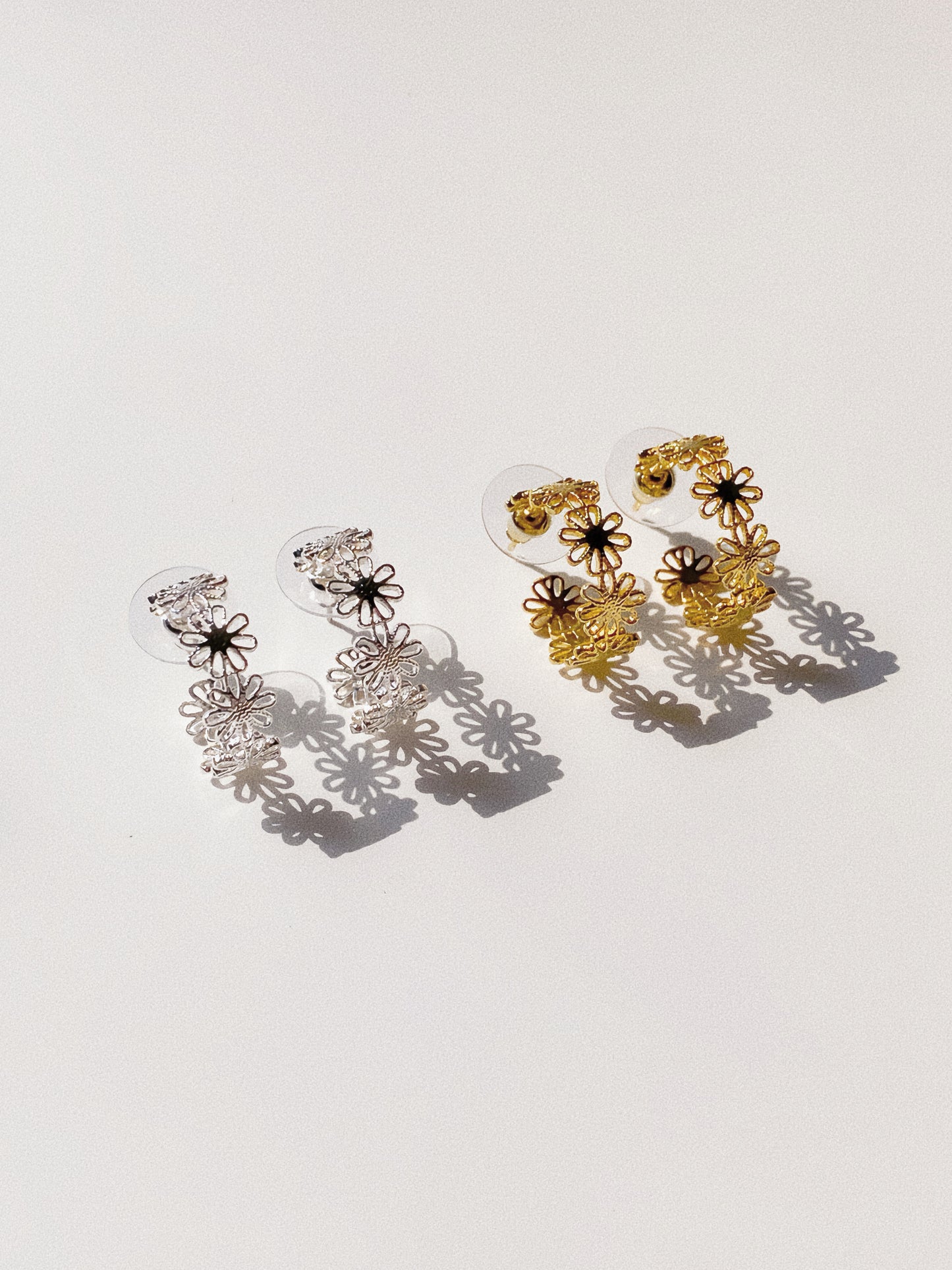 Daisy lace floral open hoop earrings in gold and silver finishes flat lay by Deja Vu Jewellery