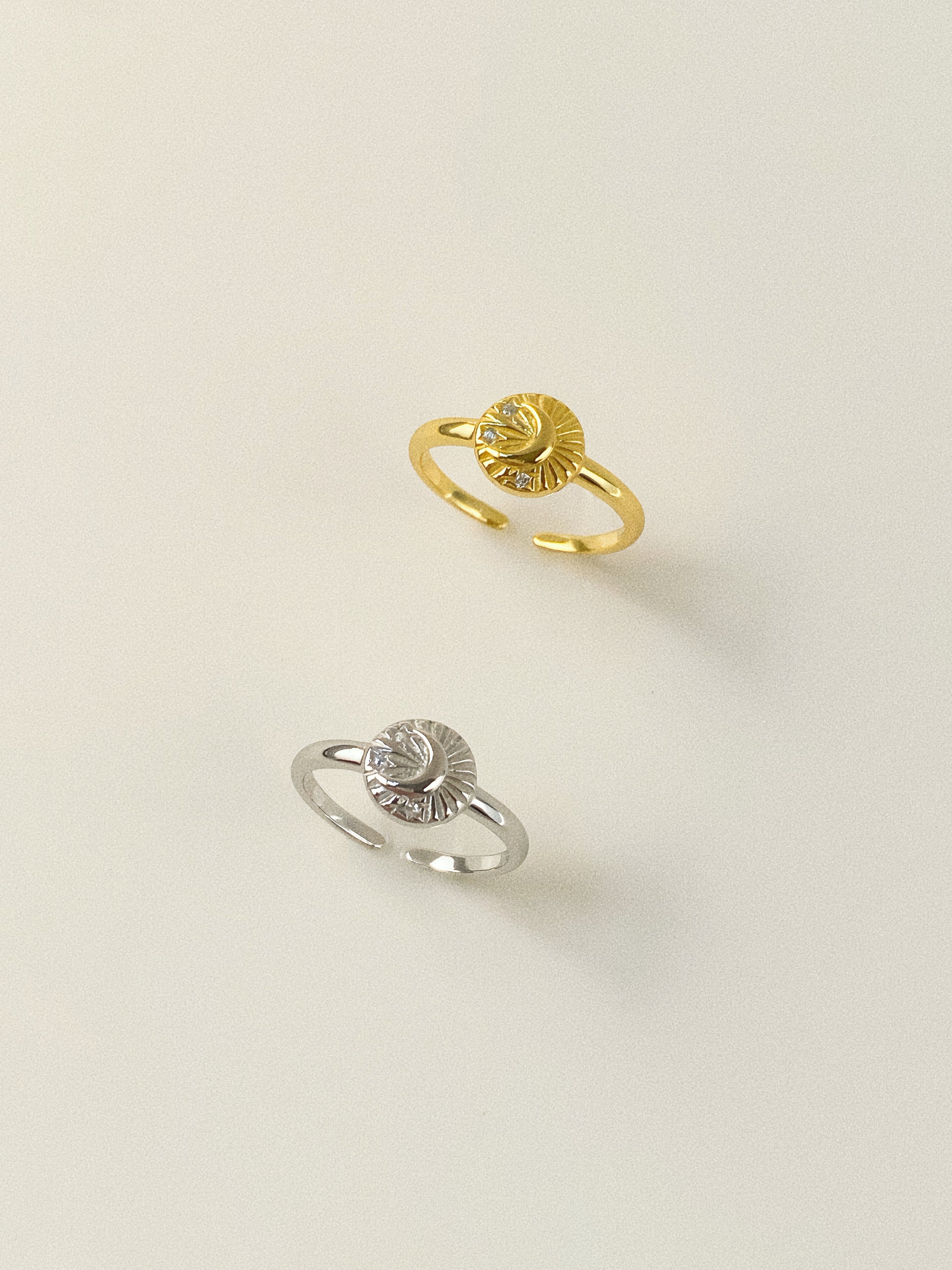 A pair of adjustable signet rings in 18k gold plated silver and 925 sterling silver with star and moon engravings.