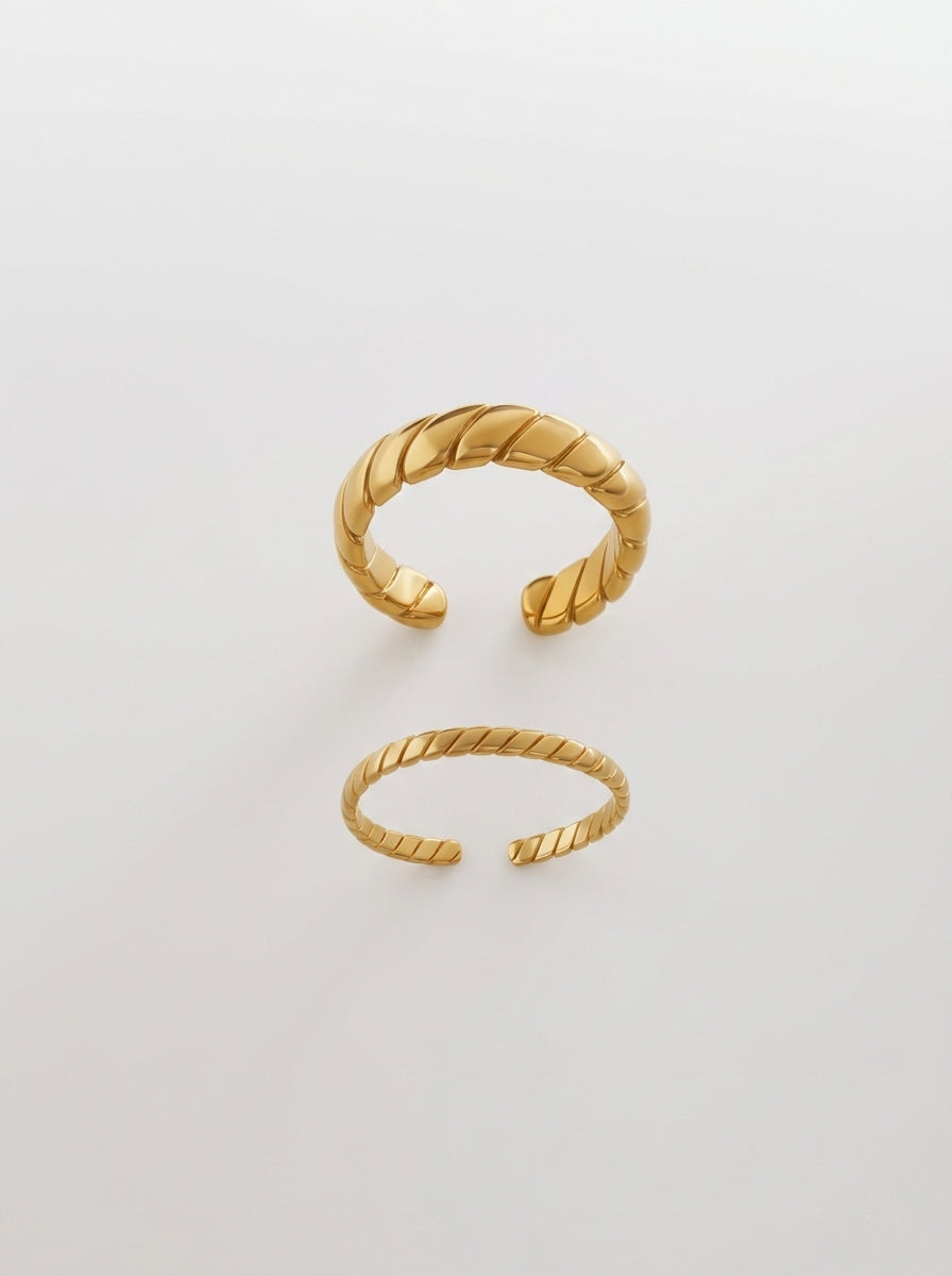 Wide and narrow gold croissant-style rings with slanted stripe patterns in 18k gold plated titanium steel.