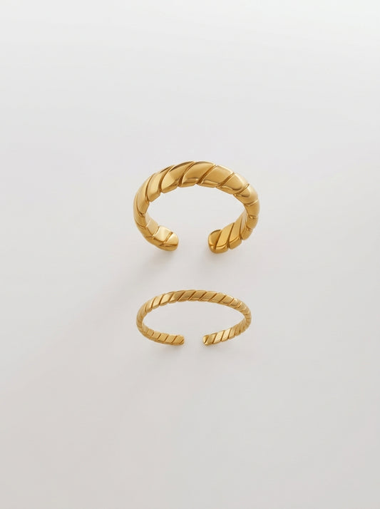 Wide and narrow gold croissant-style rings with slanted stripe patterns in 18k gold plated titanium steel.