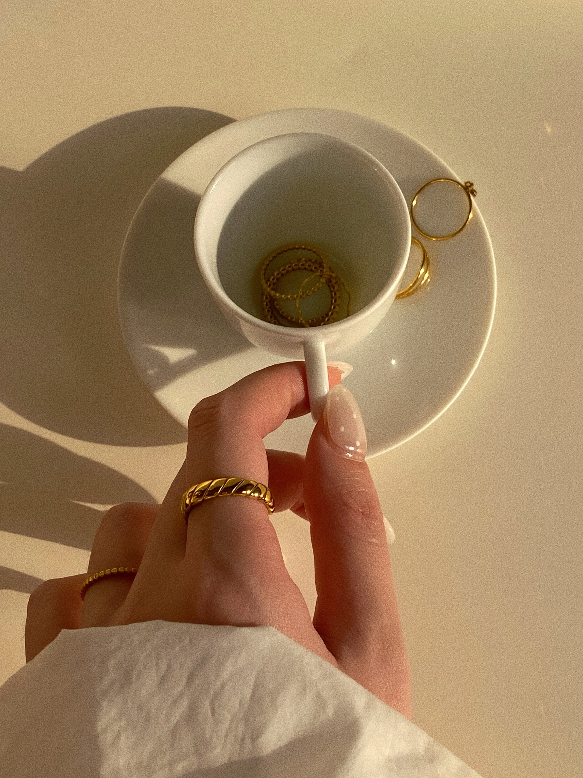 Lifestyle shot of a woman holding a coffee cup while wearing the wide gold croissant ring.