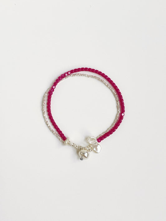 Flat lay view of a double-layer bracelet made of red ruby gemstones, crushed silver beads, and white baroque petal pearls.