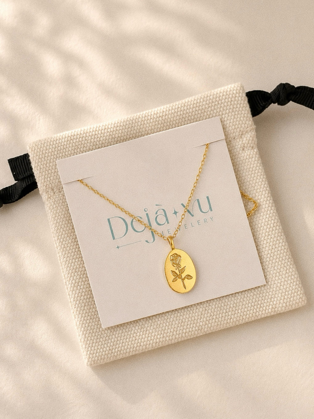Déjà Vu gold rose pendant necklace on a branded card with a canvas gift pouch