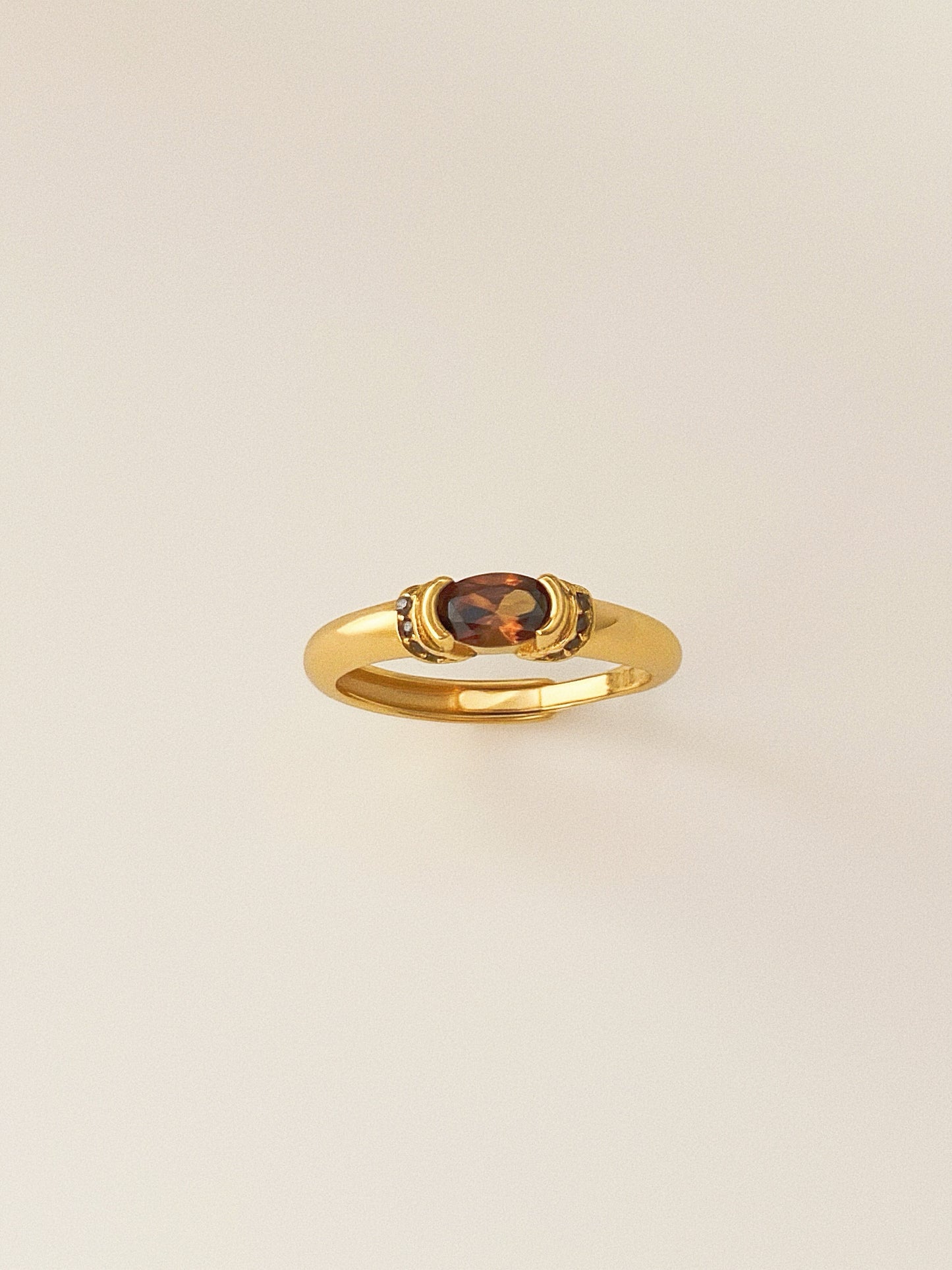A vintage-style gold ring featuring a central oval smokey quartz gemstone.