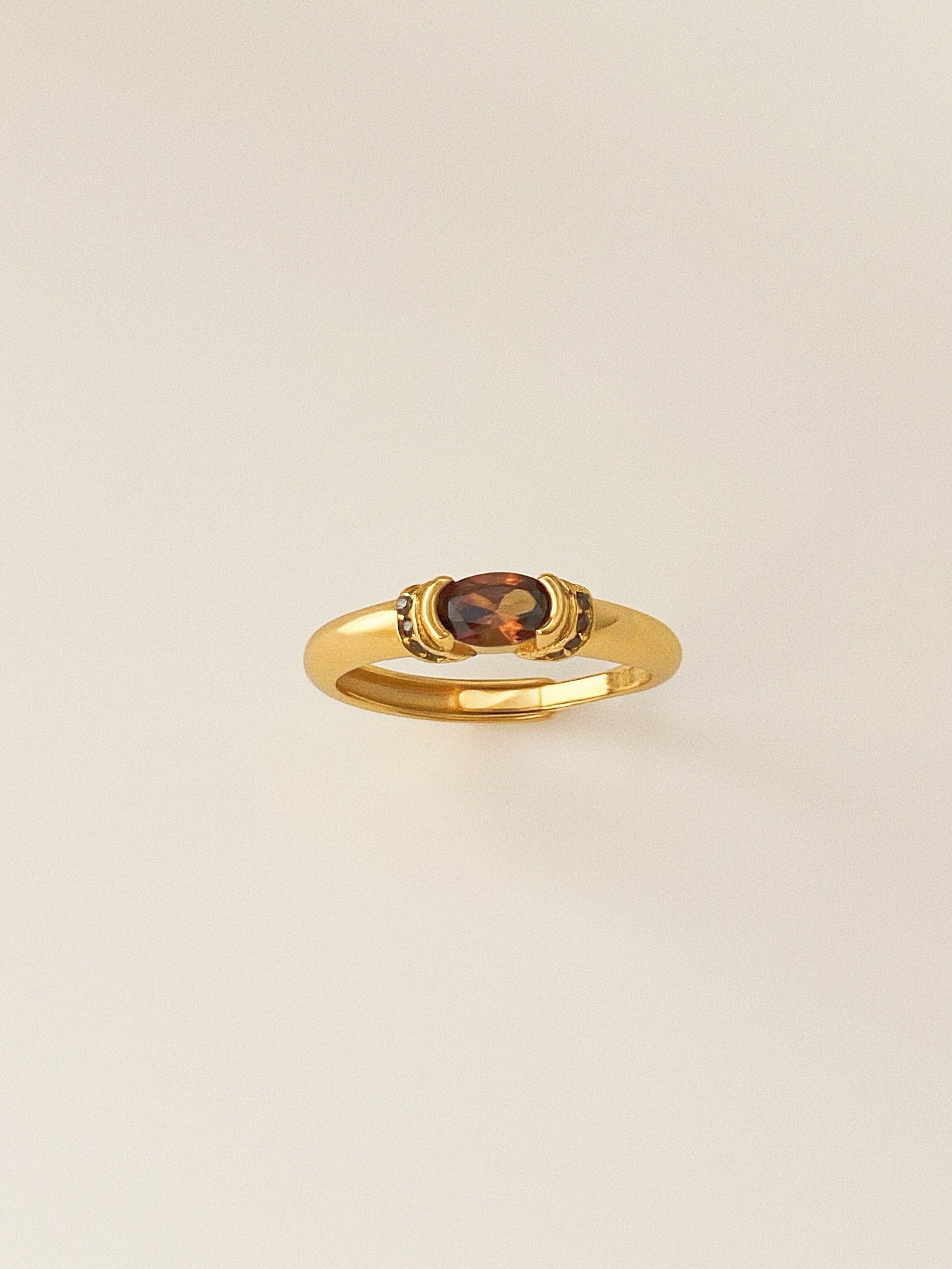 A vintage-style gold ring featuring a central oval smokey quartz gemstone.