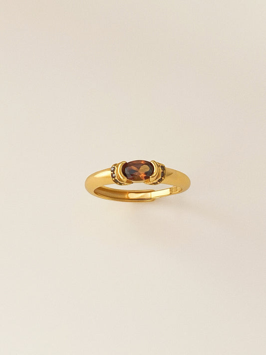 A vintage-style gold ring featuring a central oval smokey quartz gemstone.