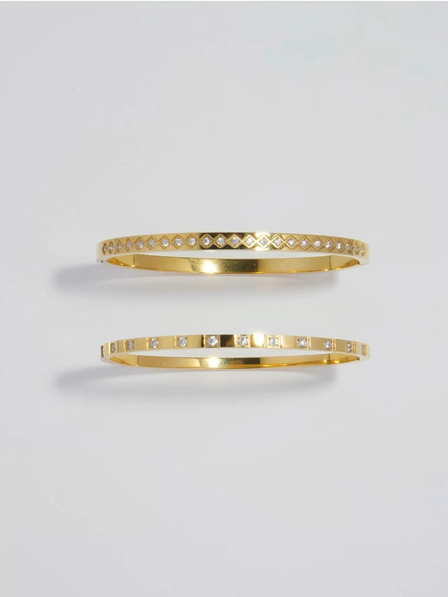 A pair of 18k gold plated stainless steel bangles featuring rhombus and square patterns from Deja vu Jewellery.