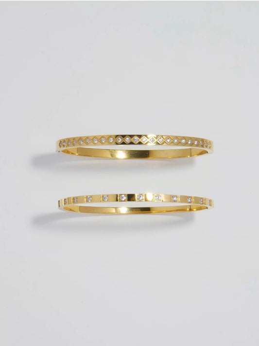 A pair of 18k gold plated stainless steel bangles featuring rhombus and square patterns from Deja vu Jewellery.