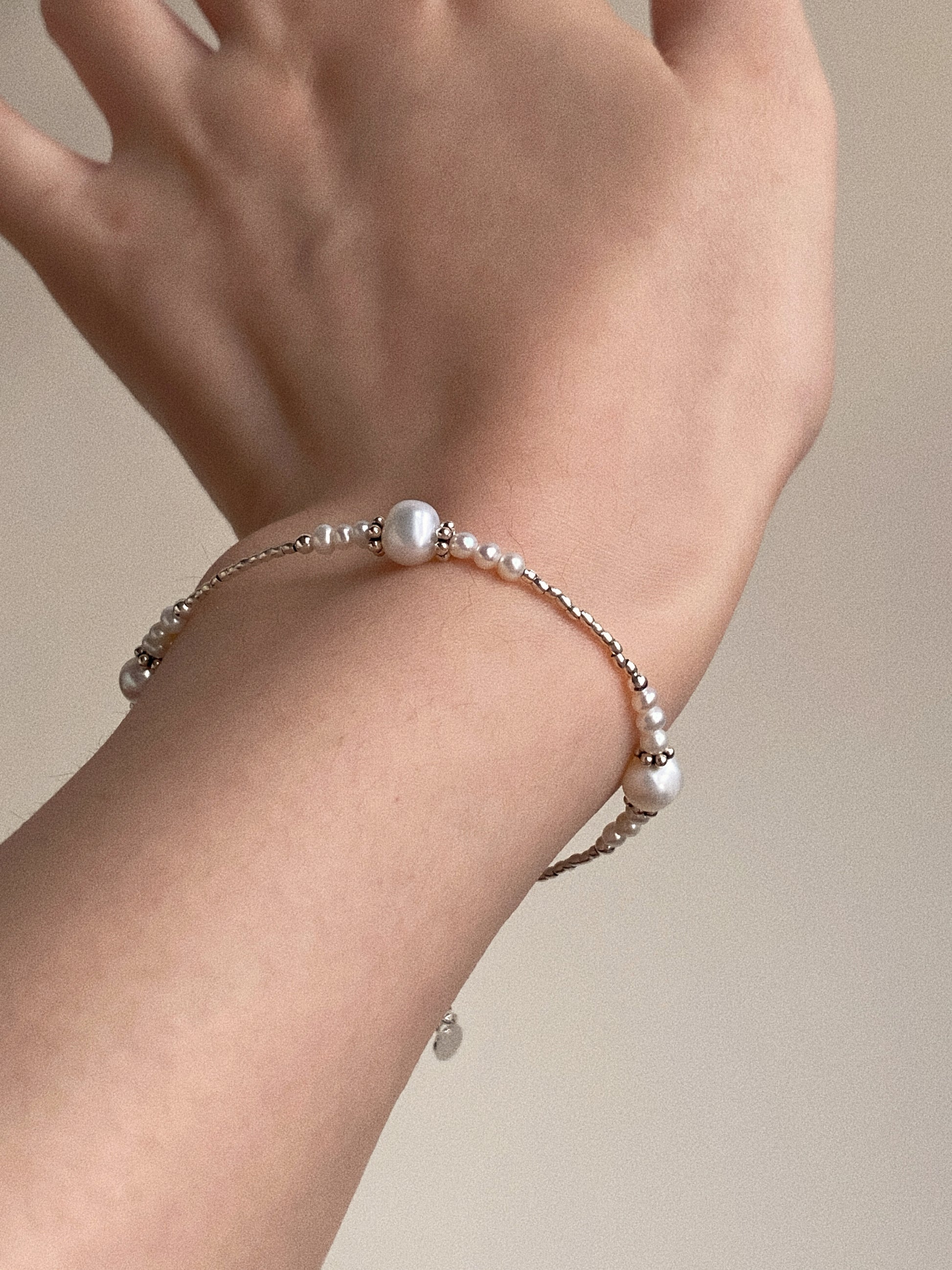 A woman wearing the minimalist freshwater pearl and silver bracelet, showcasing its perfect fit on a petite wrist.
