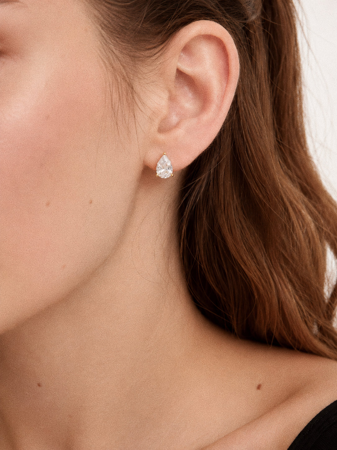 Close view of the pear cut stud earring from the Dew set worn on the ear