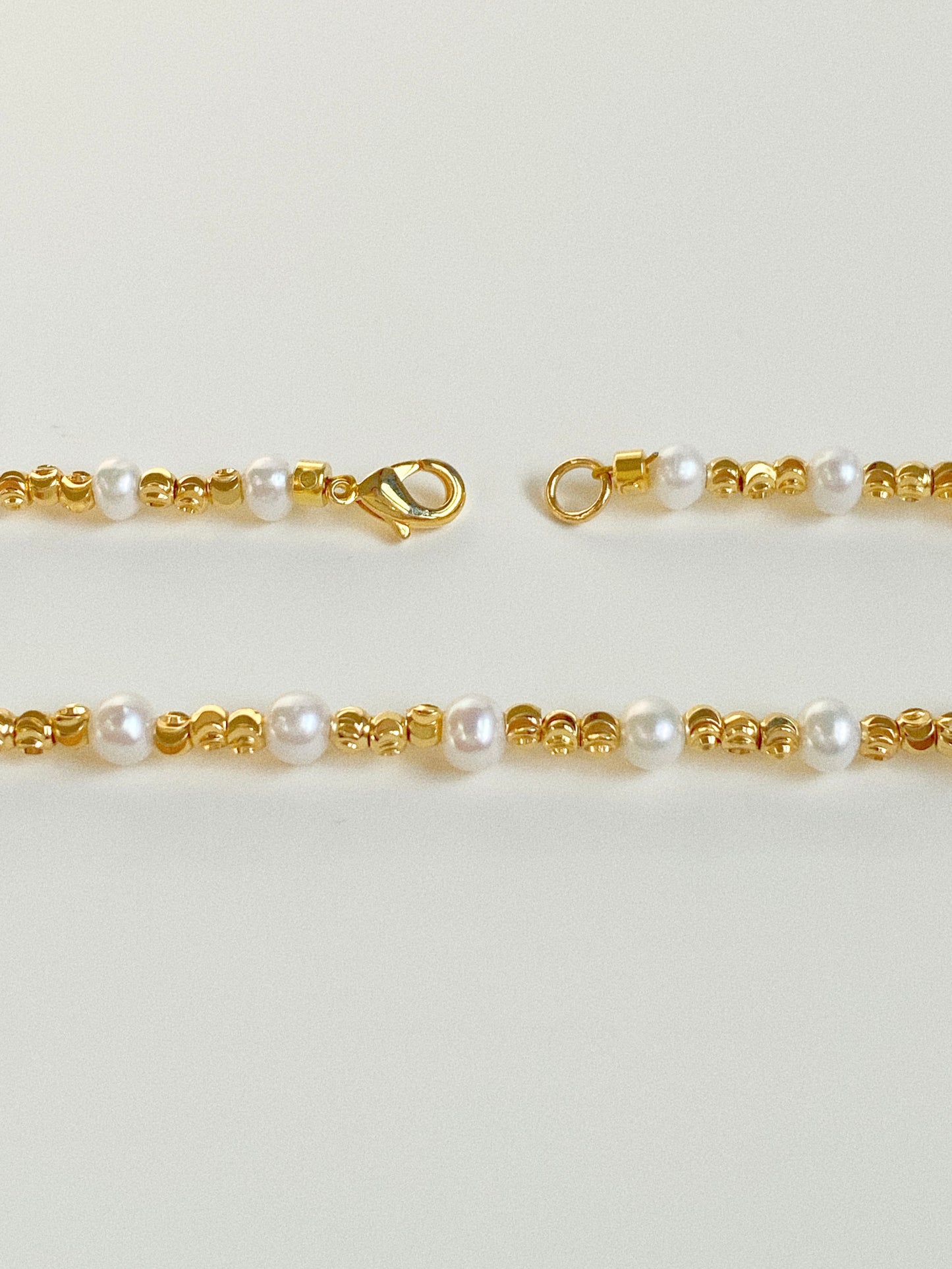 Close-up of waterproof gold lobster clasp and diamond-cut gold beads alternating with natural freshwater pearls