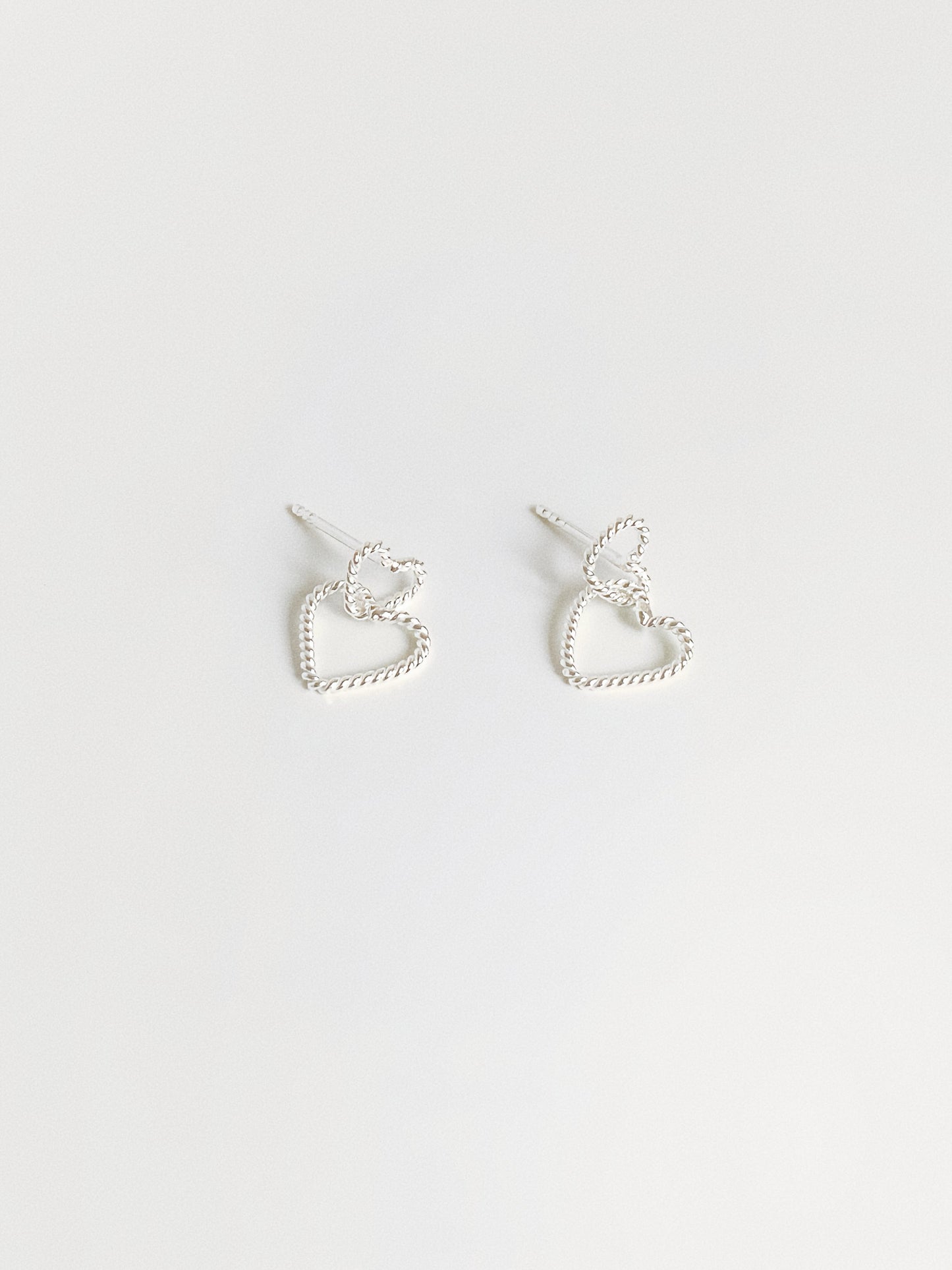 Dainty double heart stud earrings in 925 sterling silver with twisted rope texture flat lay by Deja vu Jewellery