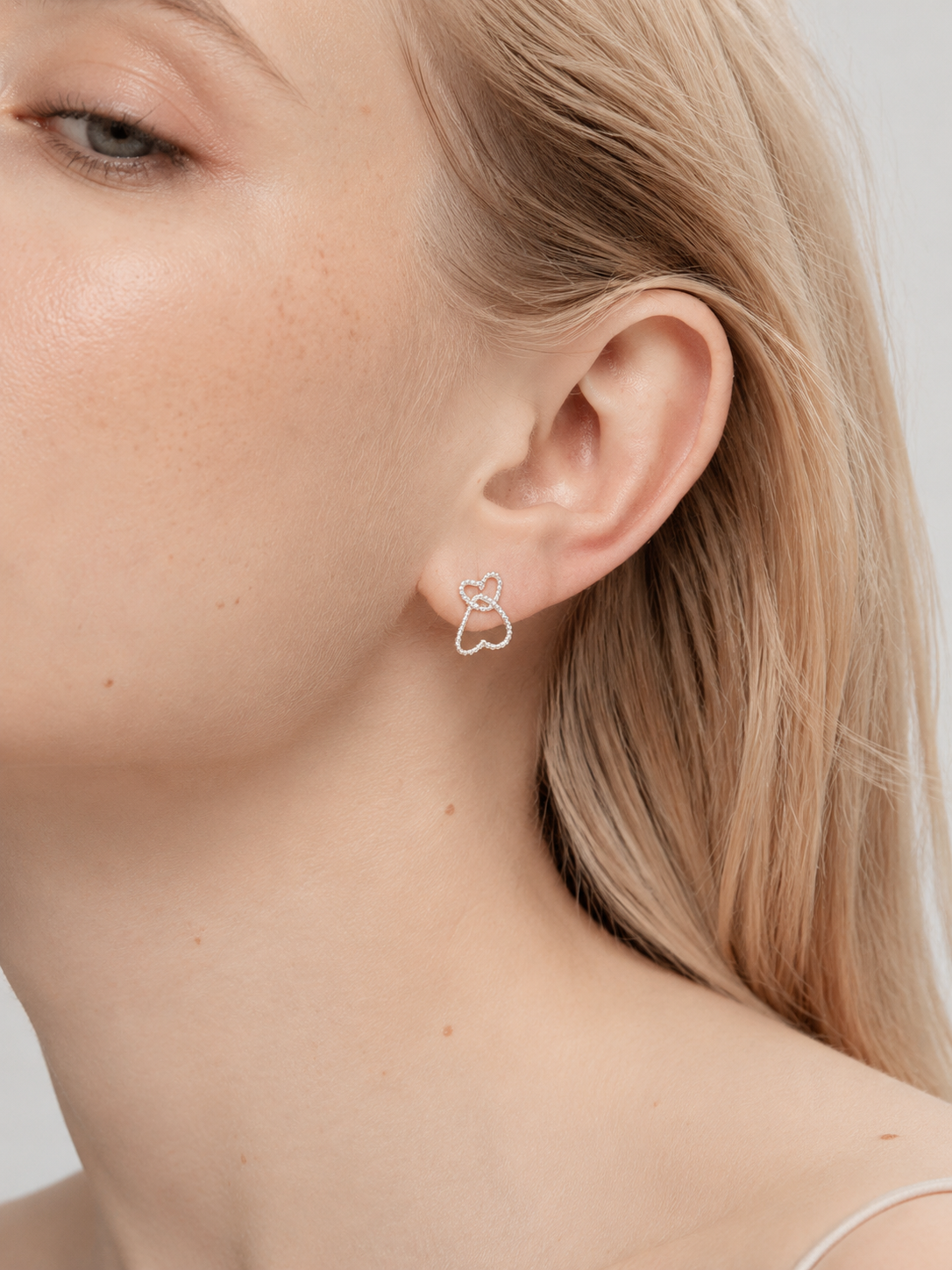 Sterling silver double heart stud earrings worn on model showing dainty 8mm by 11mm size and twisted rope detail