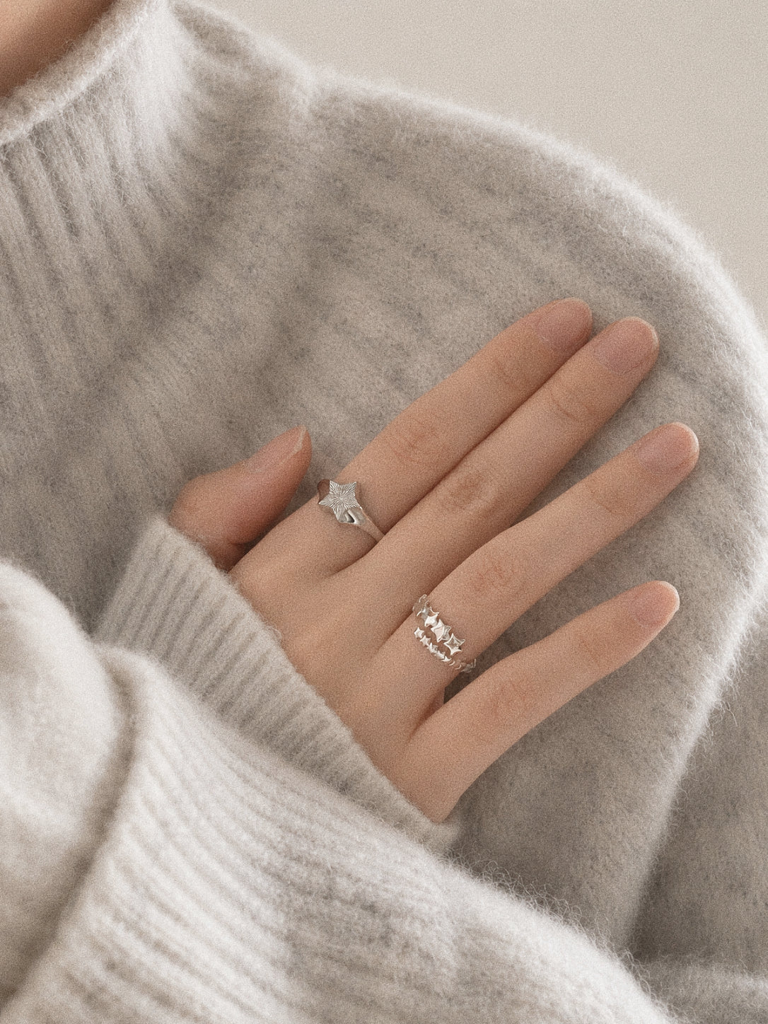 Close view of the Drift dainty multi star ring worn on the hand beside a larger silver star ring.
