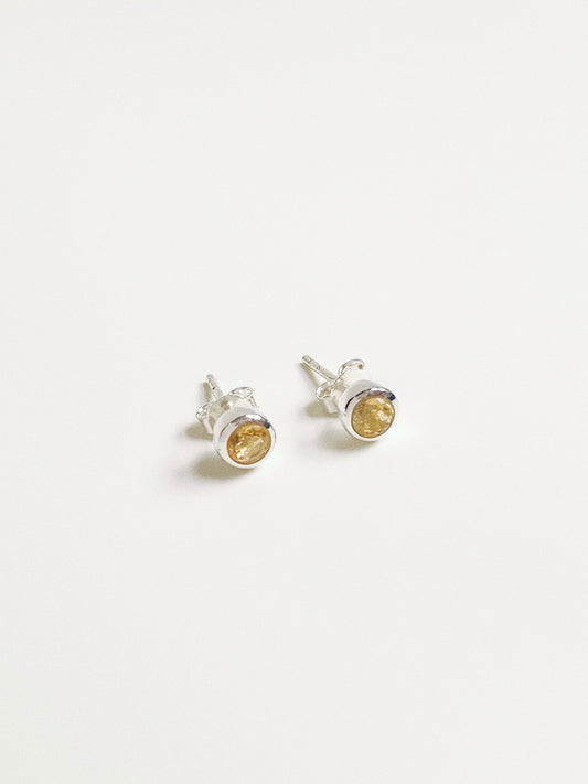 Angled view of sunny yellow citrine studs showing the faceted cut gemstone and snag-free silver bezel.