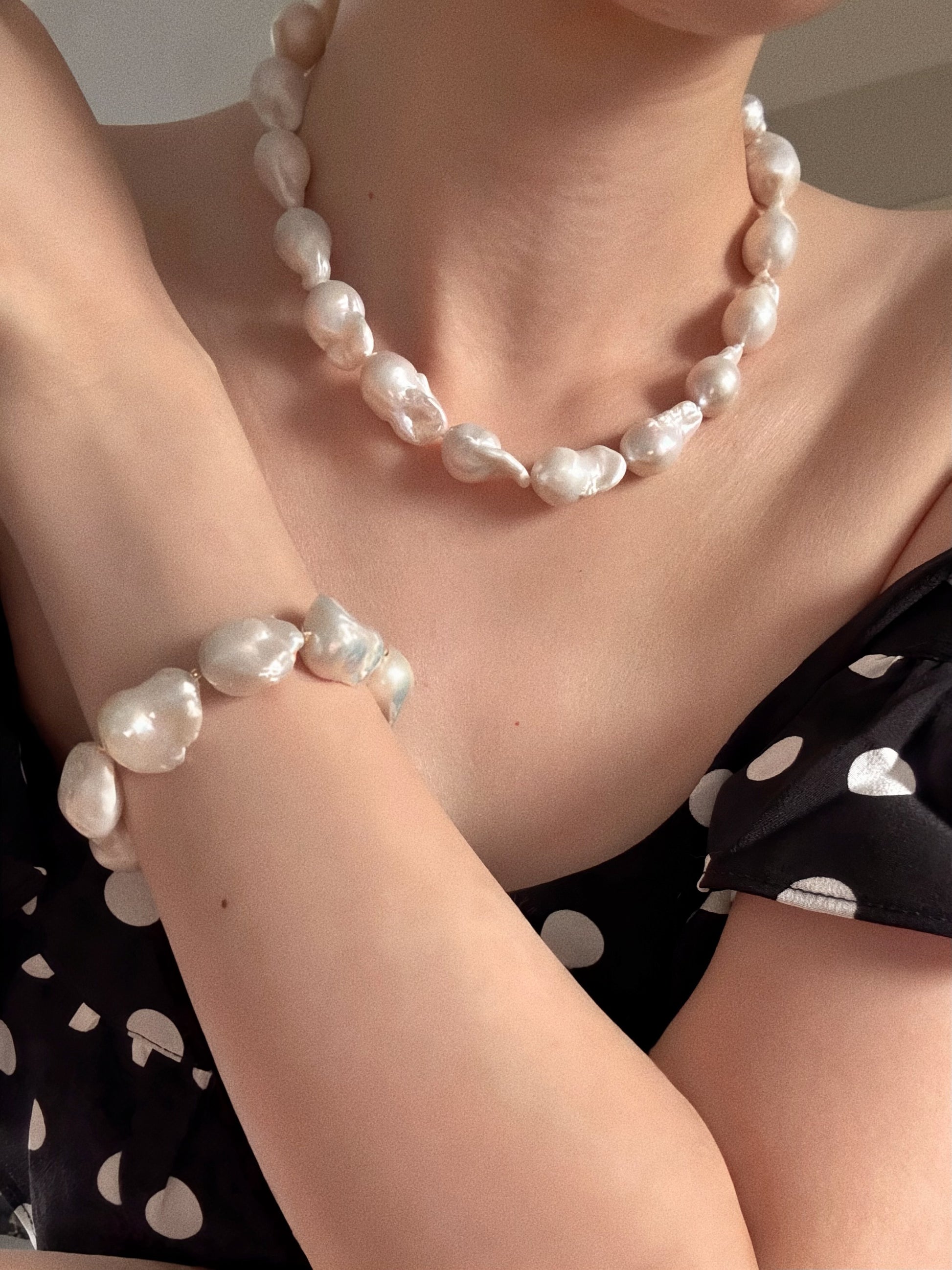 Side profile of a model wearing an 11-12mm natural baroque freshwater pearl necklace in soft warm light