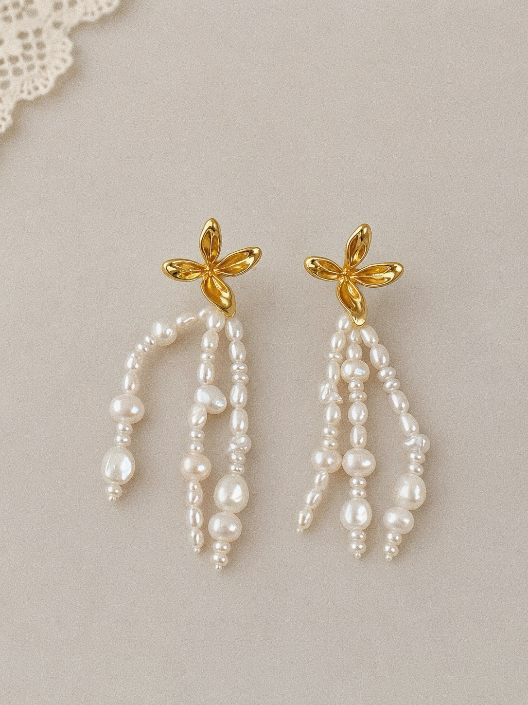 Fleur freshwater pearl tassel earrings with sculpted gold flower studs and three cascading strands of small baroque pearls.