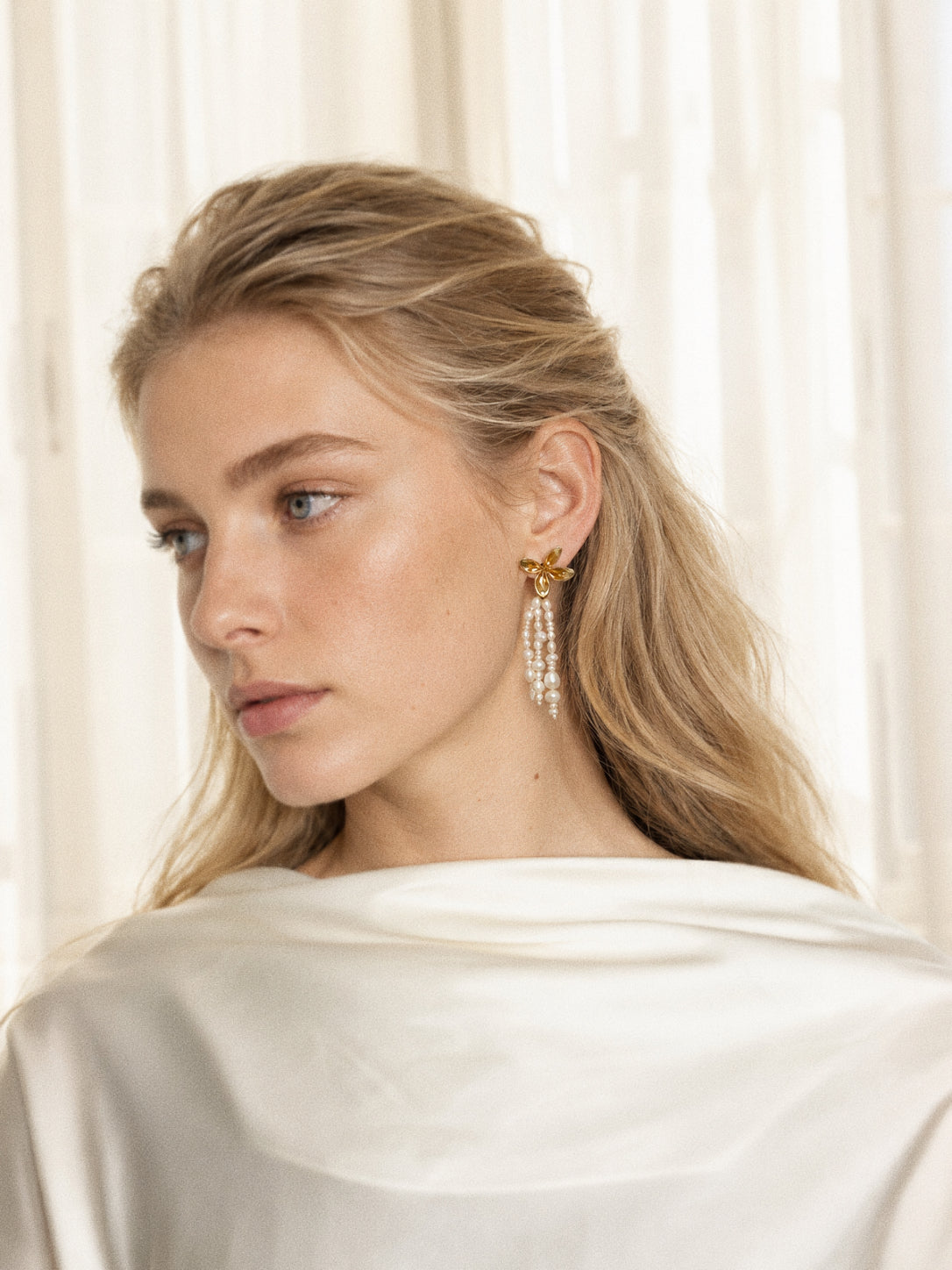 Fleur long pearl tassel earrings worn with swept-back blonde hair, showing their elegant 6.5 cm length.