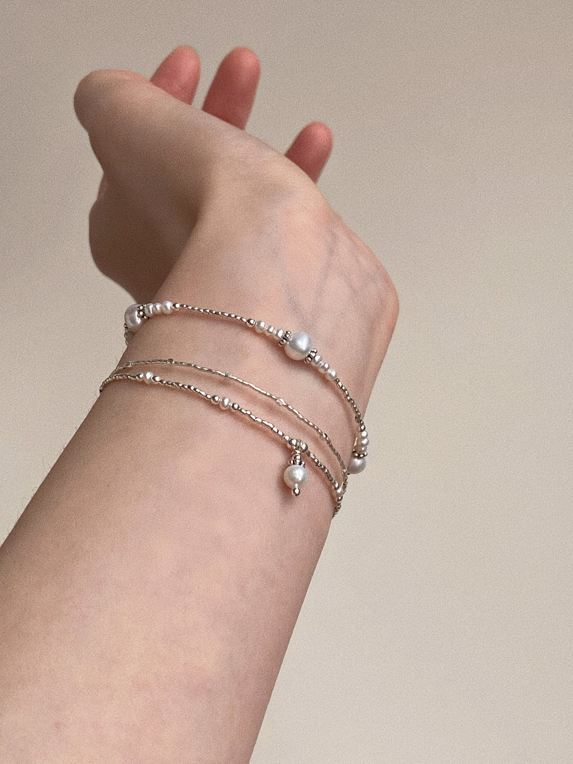 Lifestyle shot of a pearl bracelet stacked with other silver jewellery for a trendy, layered look.