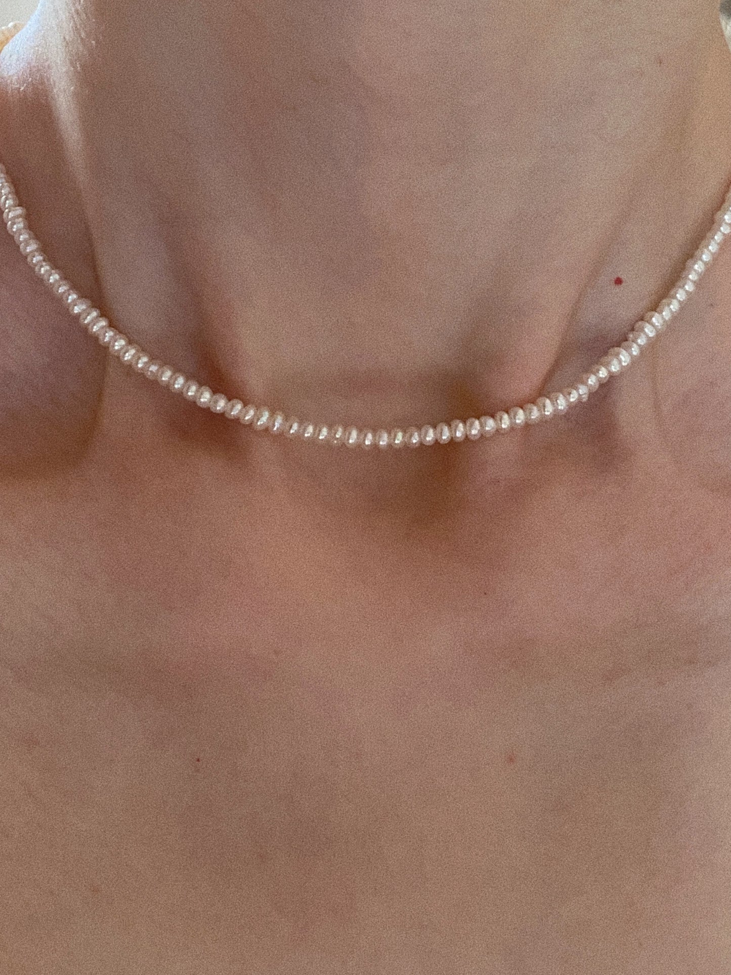 Tiny freshwater pearl choker sitting on collarbone close-up showing dainty everyday styling