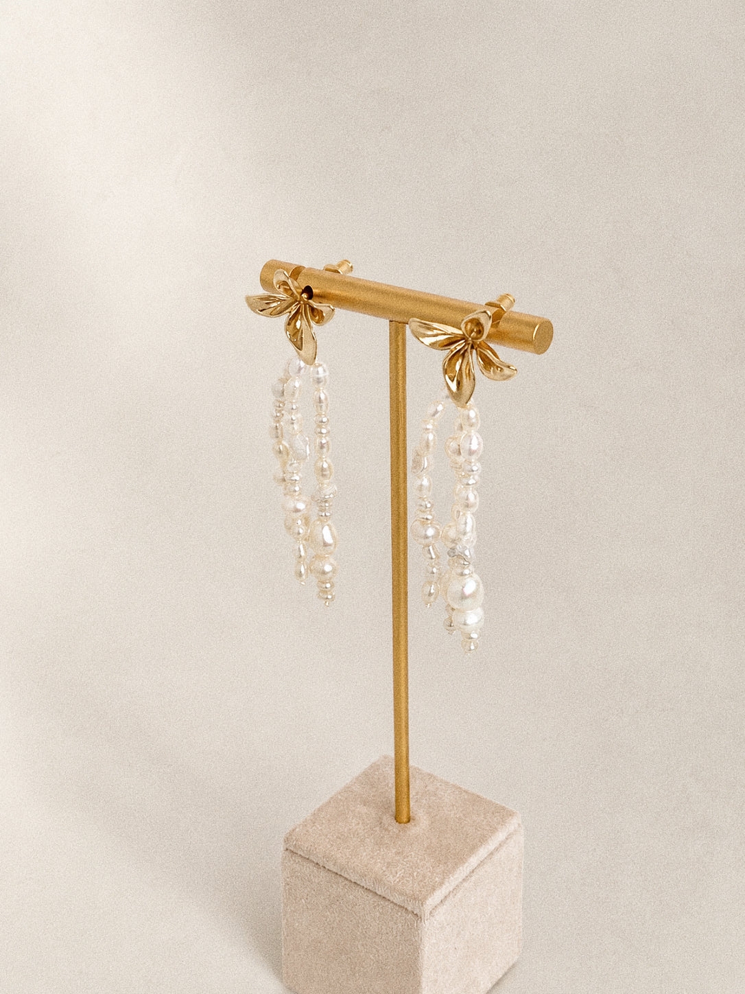 Side view of the freshwater pearl fringe earrings on a stand, showing the flower studs and layered pearl strands.