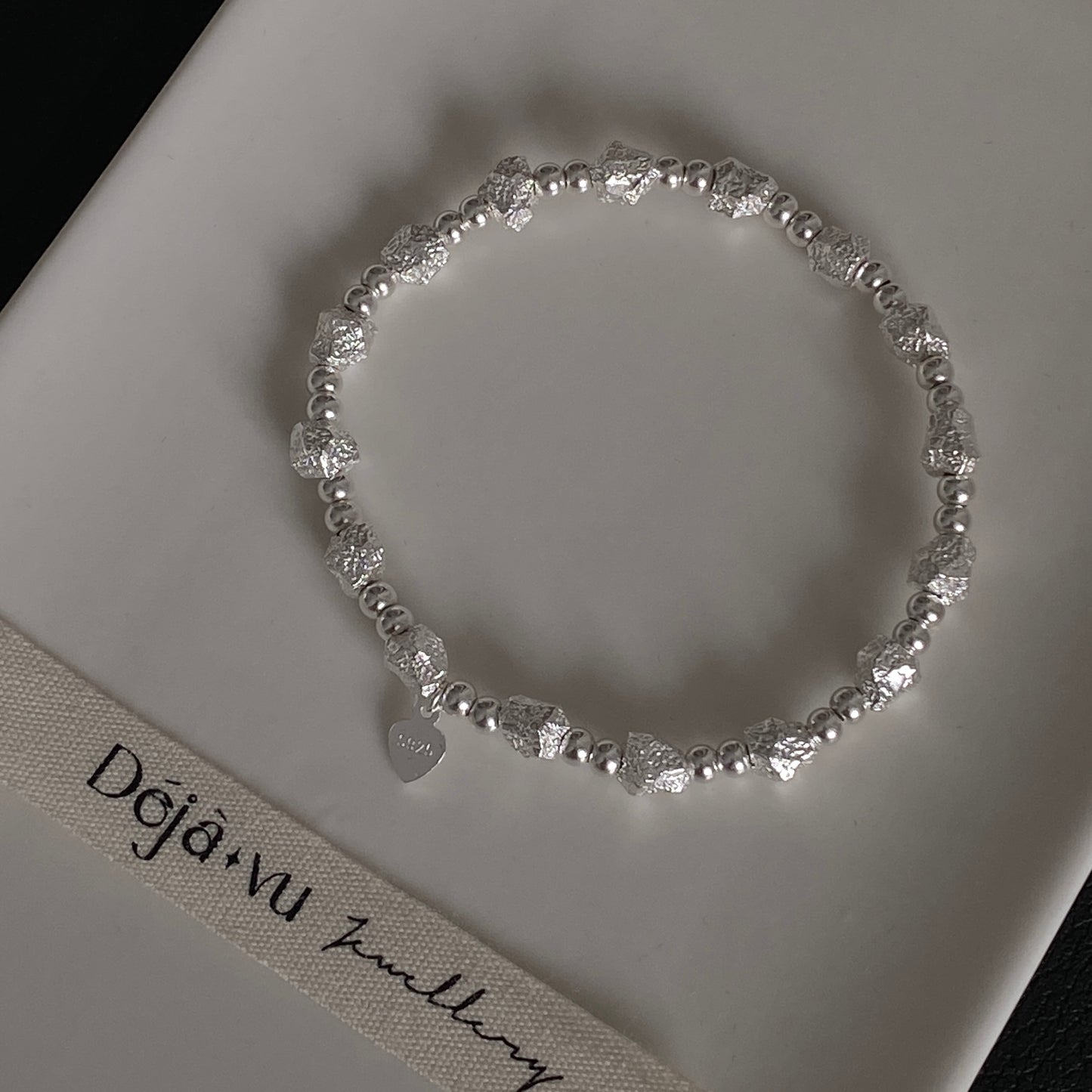 Close up macro shot of 11.5g solid silver nugget beads and S925 heart tag, highlighting the raw crushed rock texture.