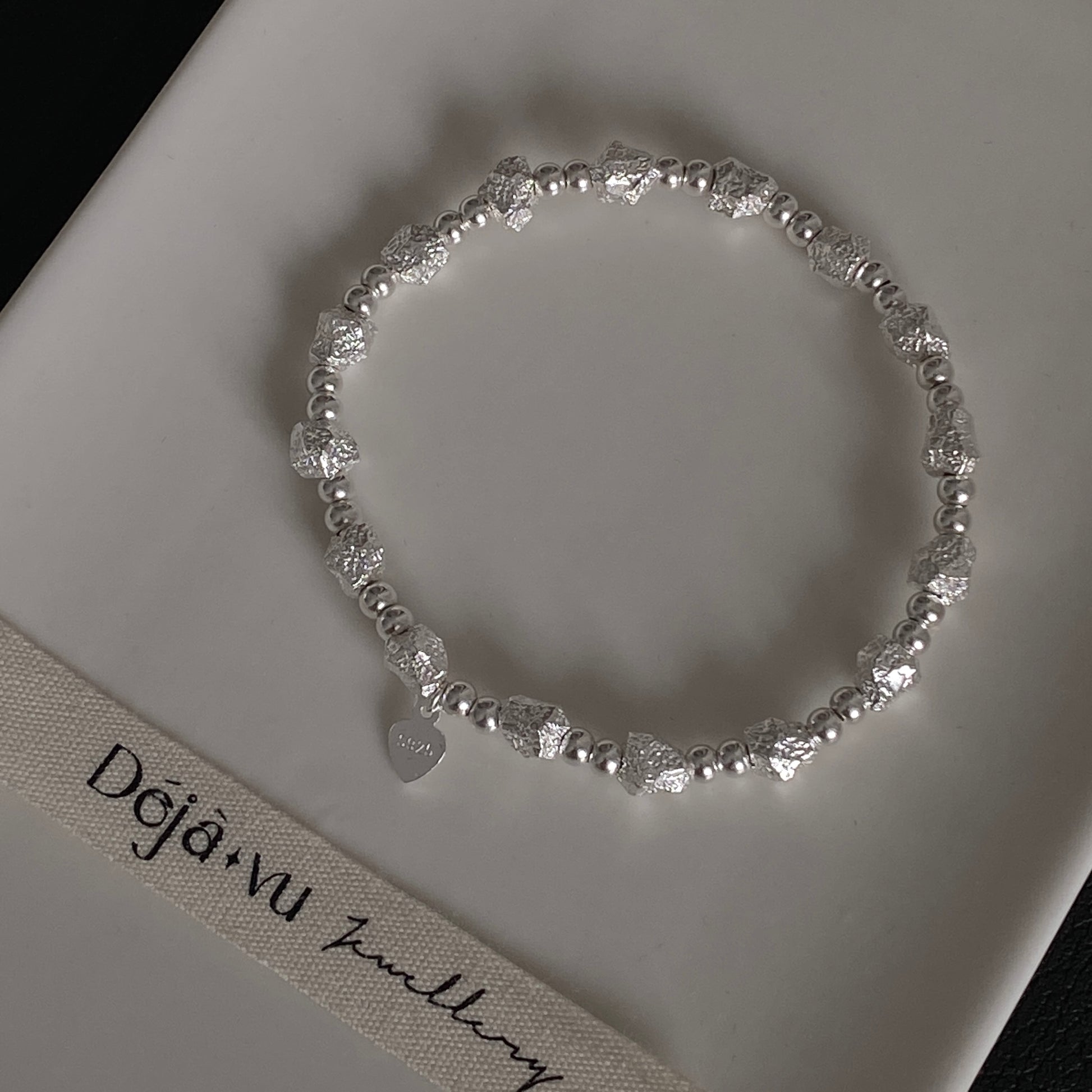 Close up macro shot of 11.5g solid silver nugget beads and S925 heart tag, highlighting the raw crushed rock texture.