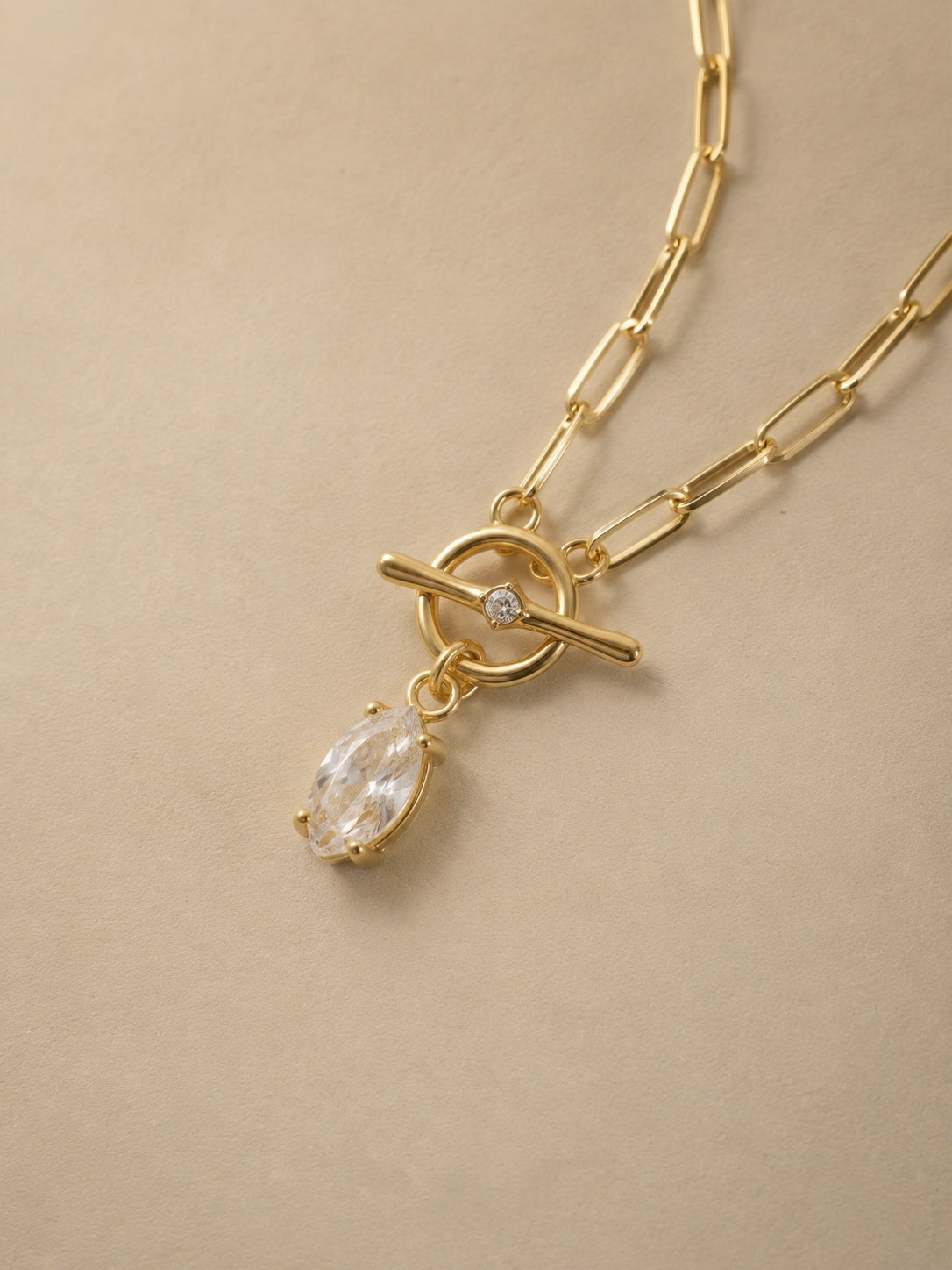 Close-up of the gold front toggle clasp with a tiny set crystal and a marquise cut cubic zirconia teardrop drop