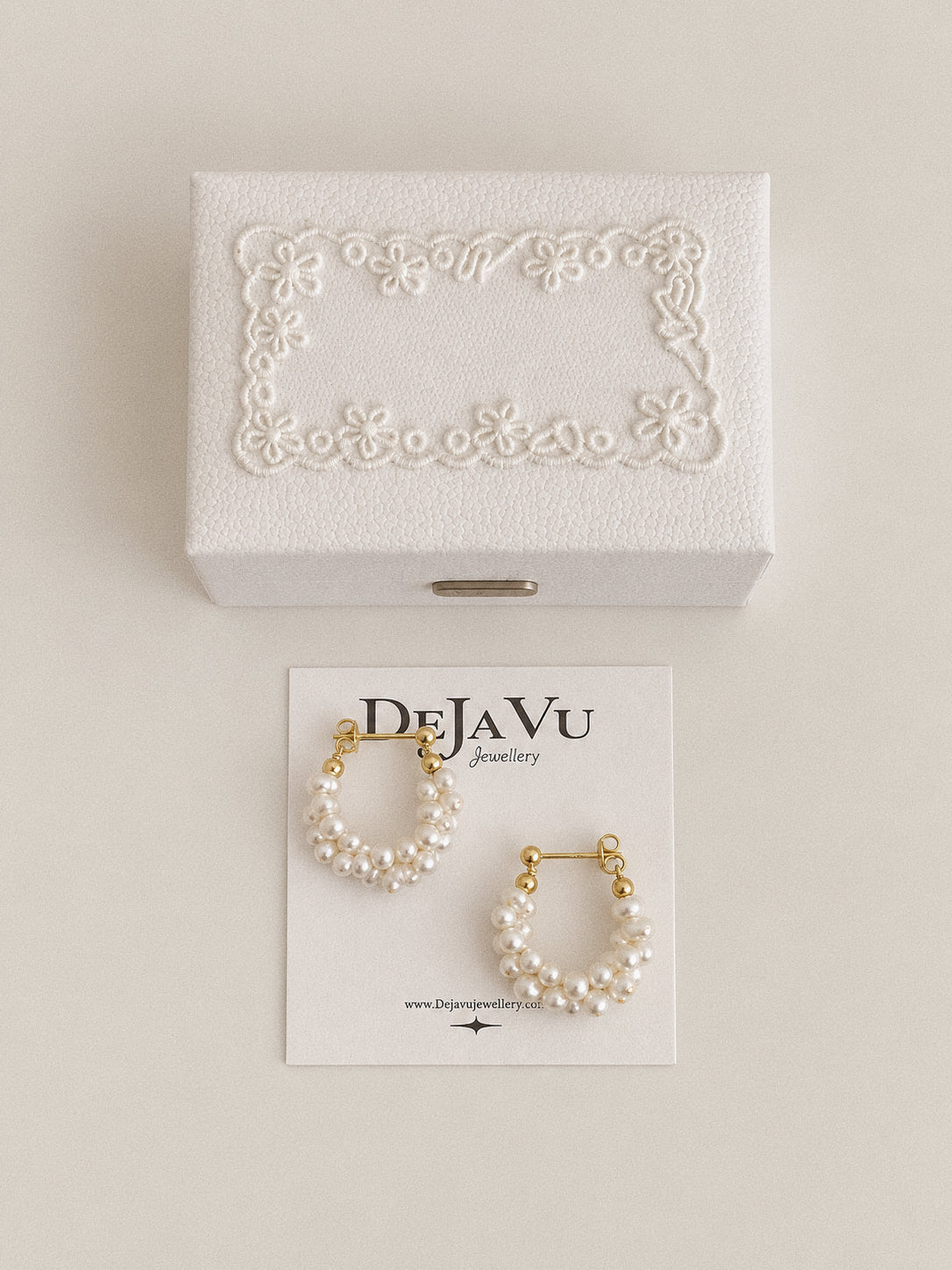 Garland freshwater pearl hoop earrings on a Deja vu Jewellery card beneath a white box with floral decoration.