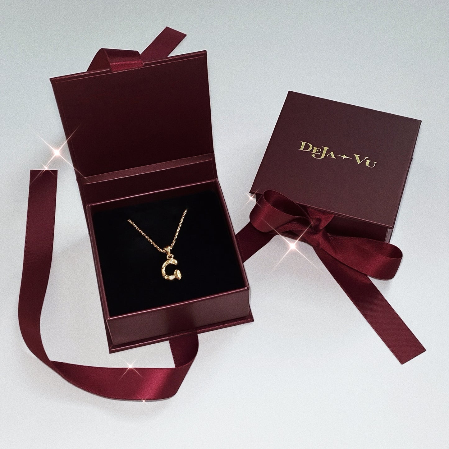 Open burgundy Deja Vu jewellery gift box revealing an 18k gold vermeil Molten Initial necklace letter G.
