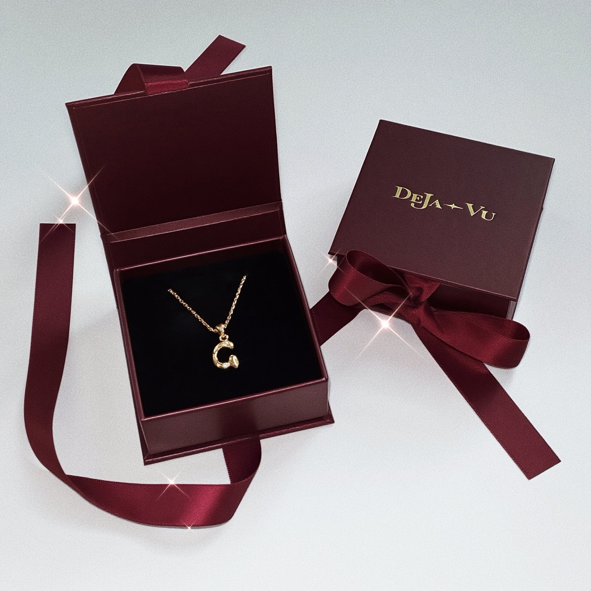 Open burgundy Deja Vu jewellery gift box revealing an 18k gold vermeil Molten Initial necklace letter G.