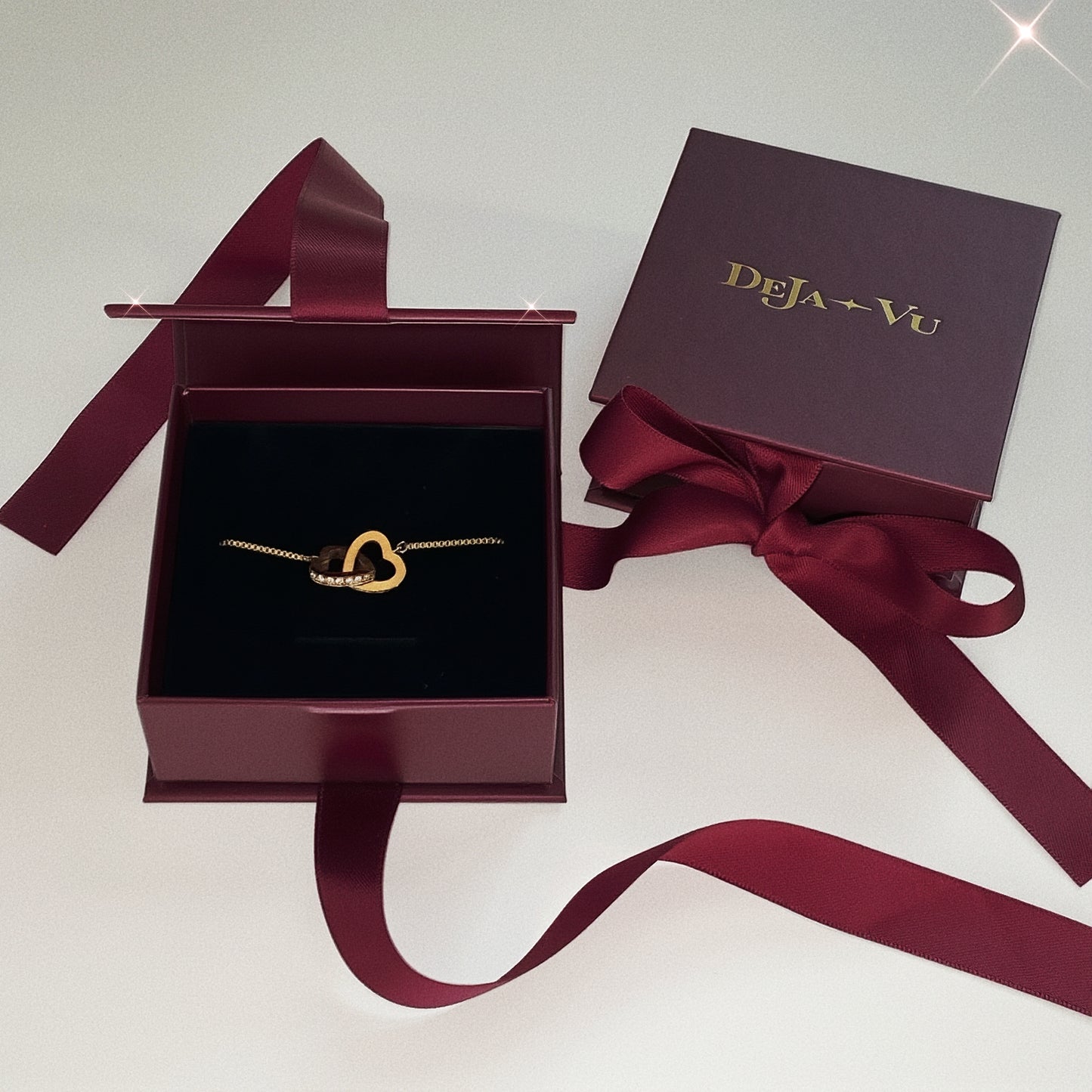 Deja vu burgundy jewellery box containing a gold interlocking heart bracelet, the perfect Valentine's Day gift for her.