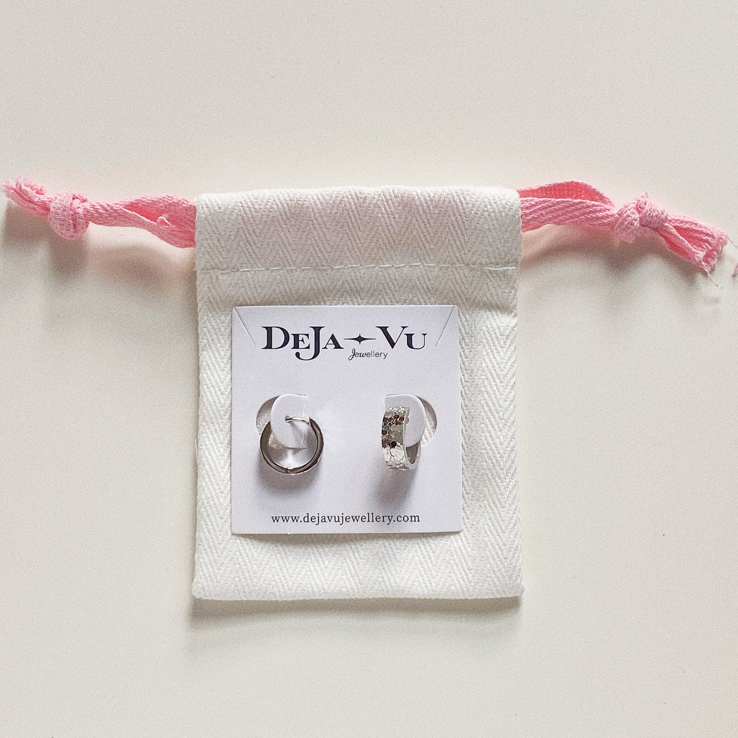 Deja Vu Jewellery packaging with silver huggie earrings pinned on card, ready for gifting.