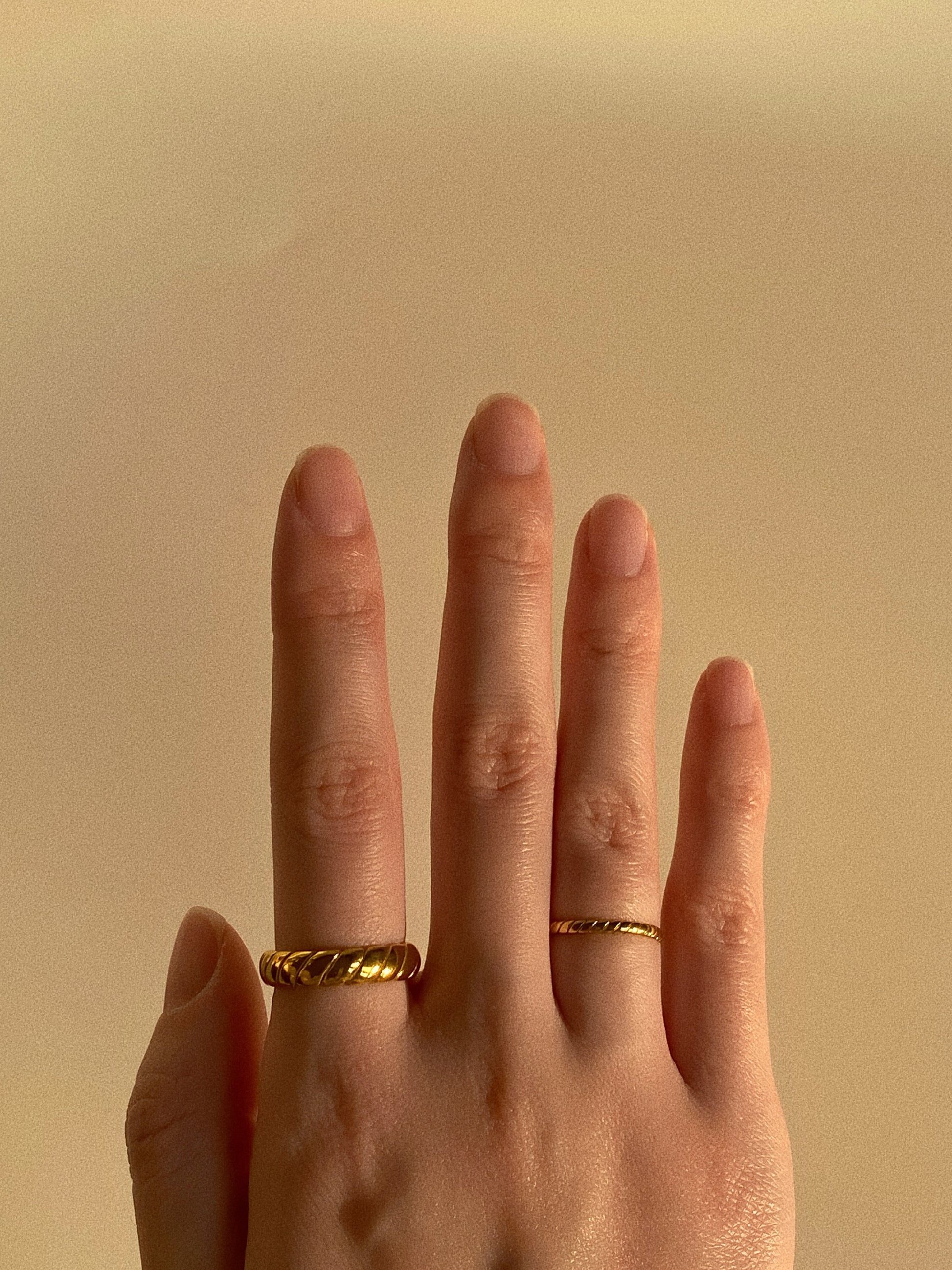 A woman wearing both the wide and narrow gold croissant rings, showcasing a modern ring stack.