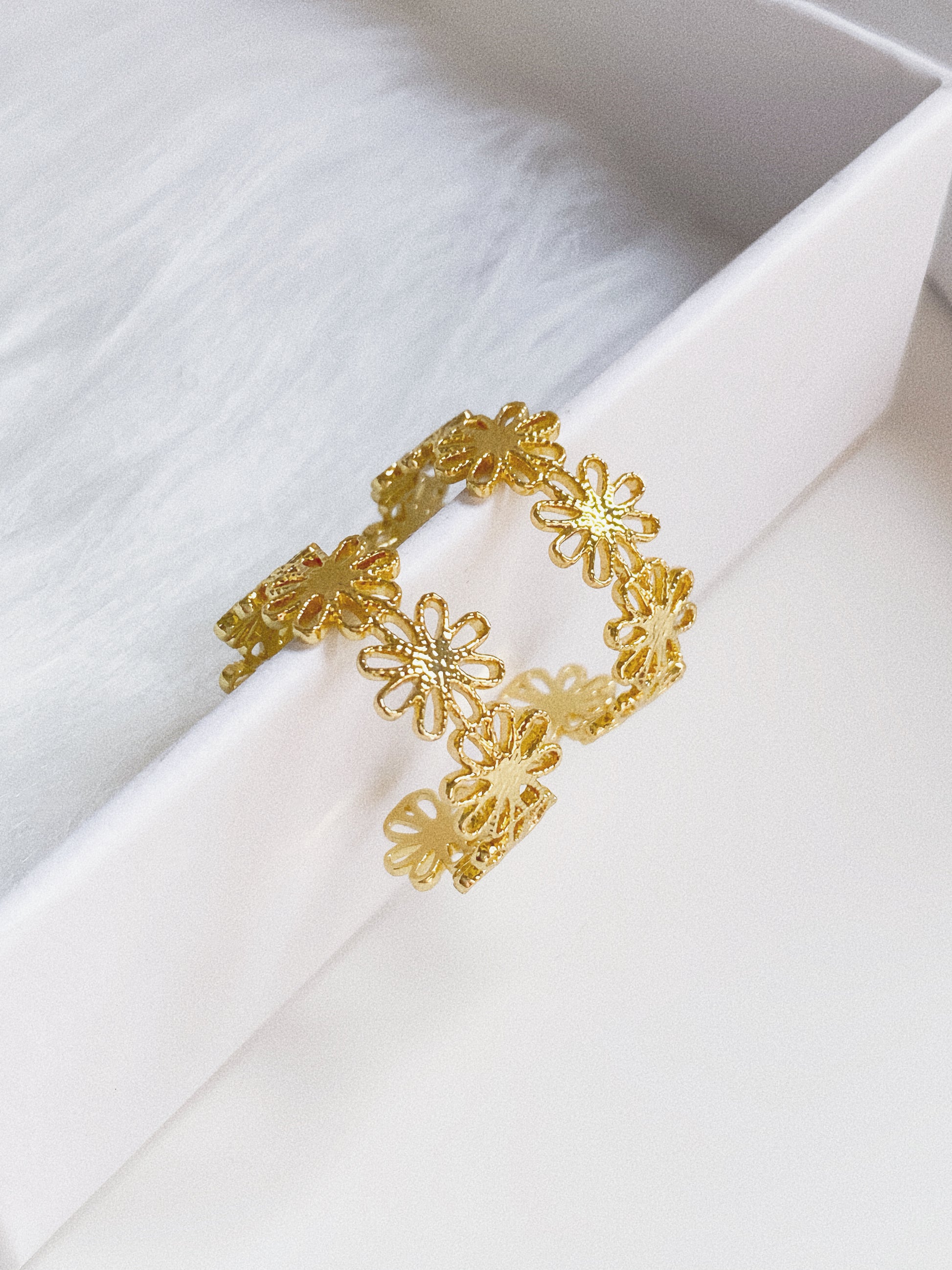 Close-up of gold daisy lace hoop earring showing fine floral lacework texture