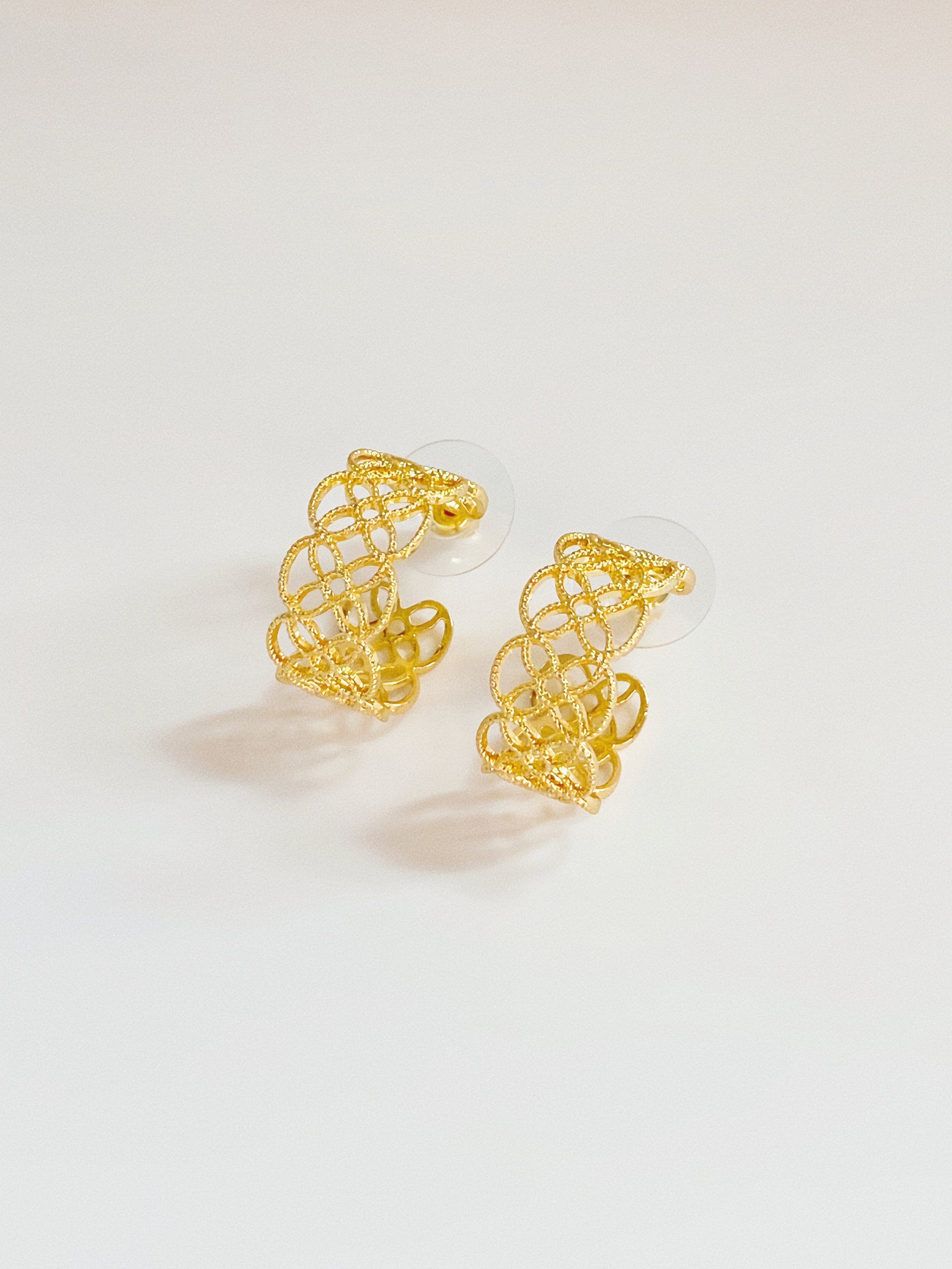 Close-up shot of the gold Arabesque Petal hoops showing the delicate cut-out craftsmanship.