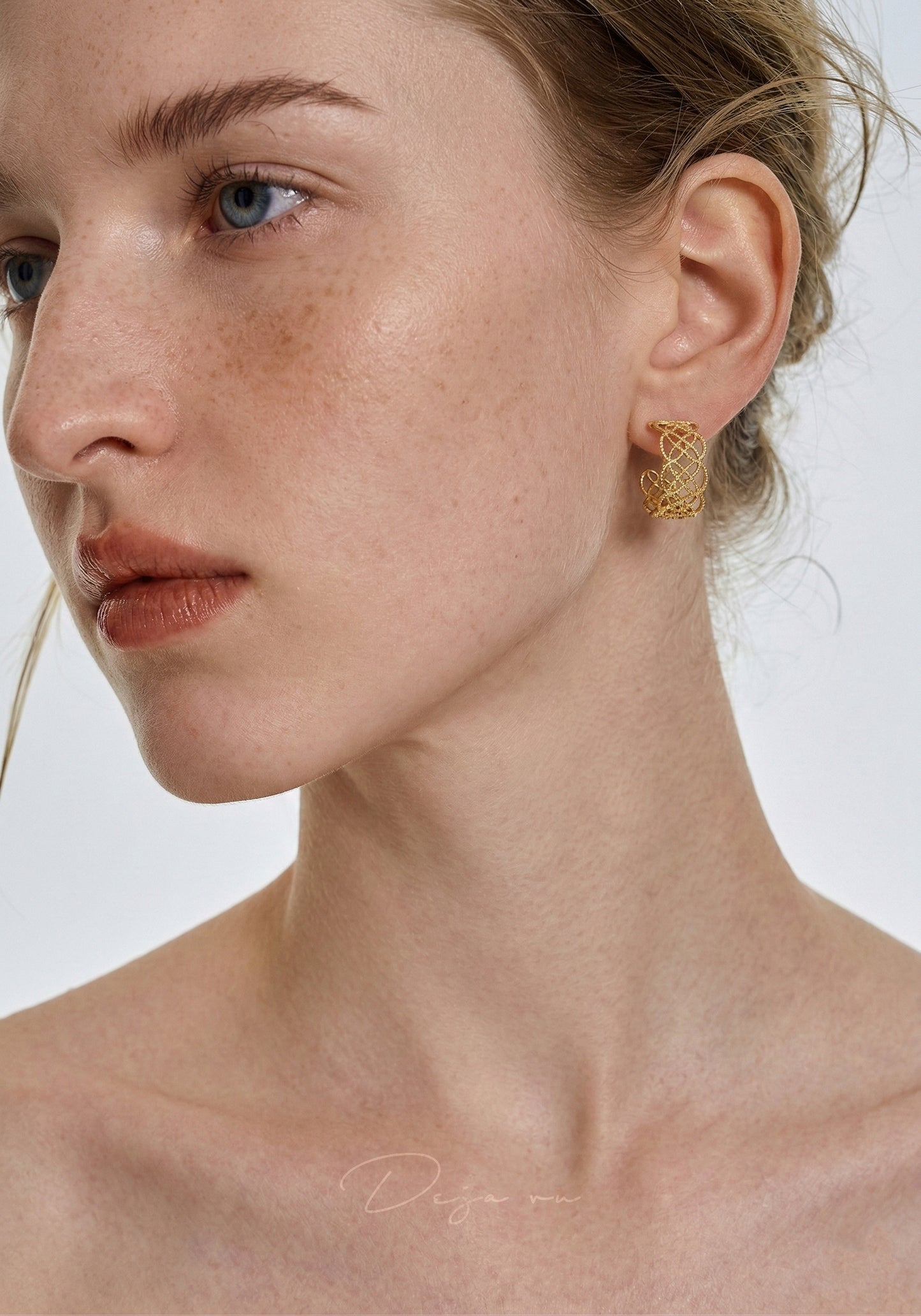 A close-up lifestyle shot highlighting the intricate lace texture of the gold hoops on a model.