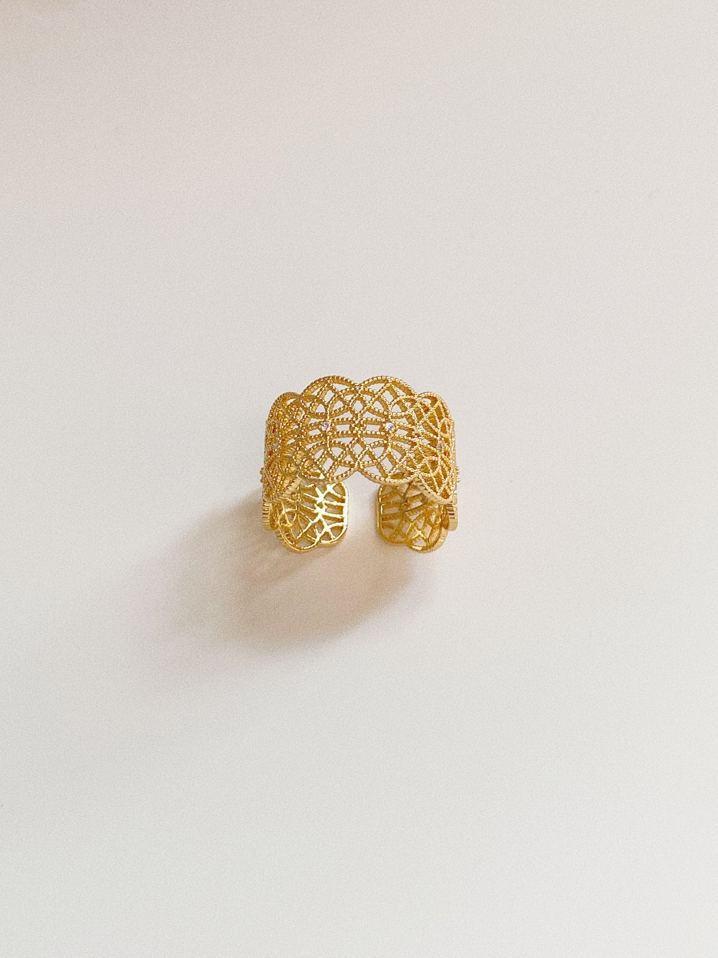 Close-up of the wide gold Gossamer Bloom ring showing the intricate floral lace cut-out pattern.
