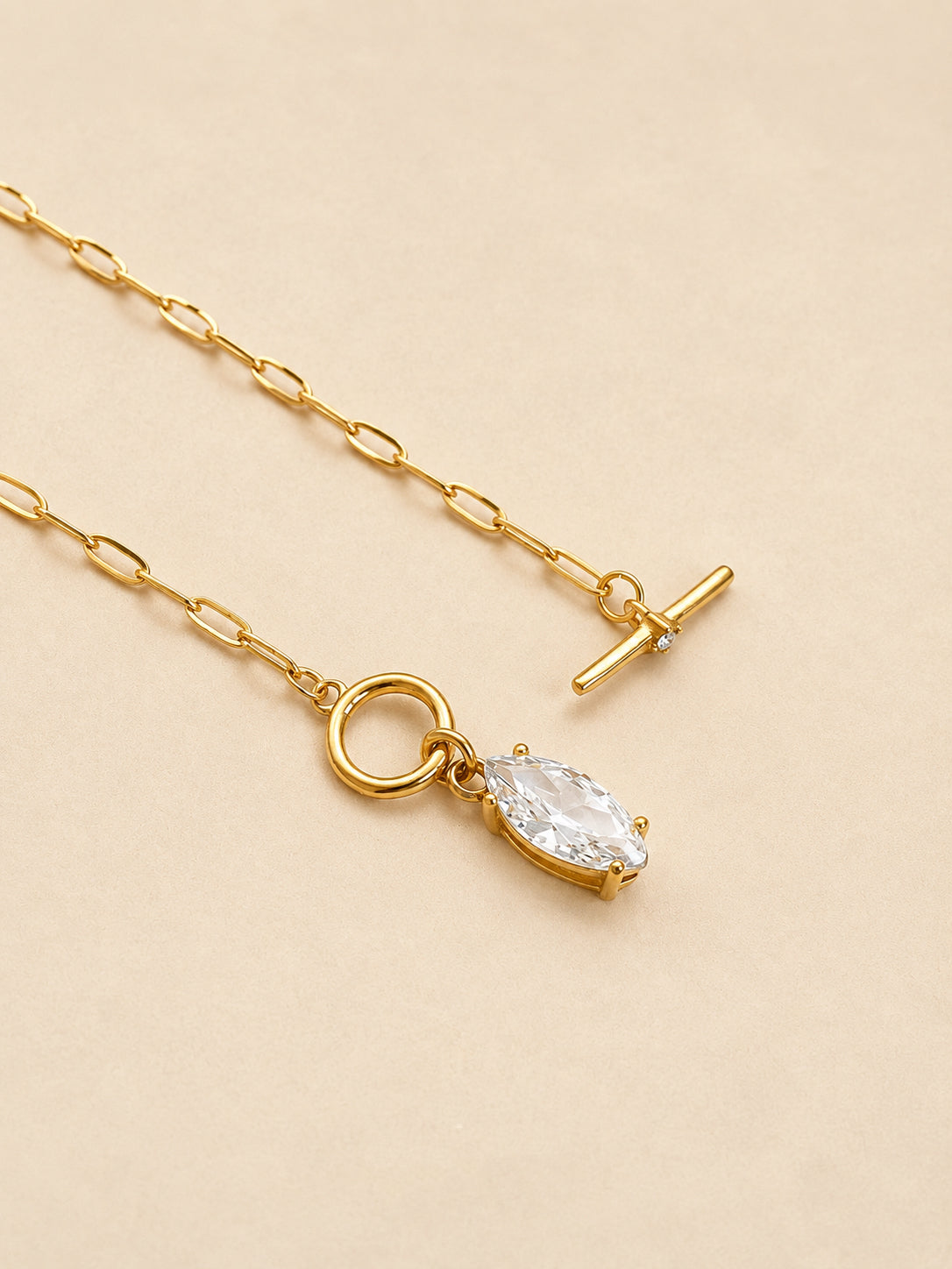 Angled view of a gold paperclip chain necklace showing the T-bar toggle clasp and prong-set marquise zircon drop