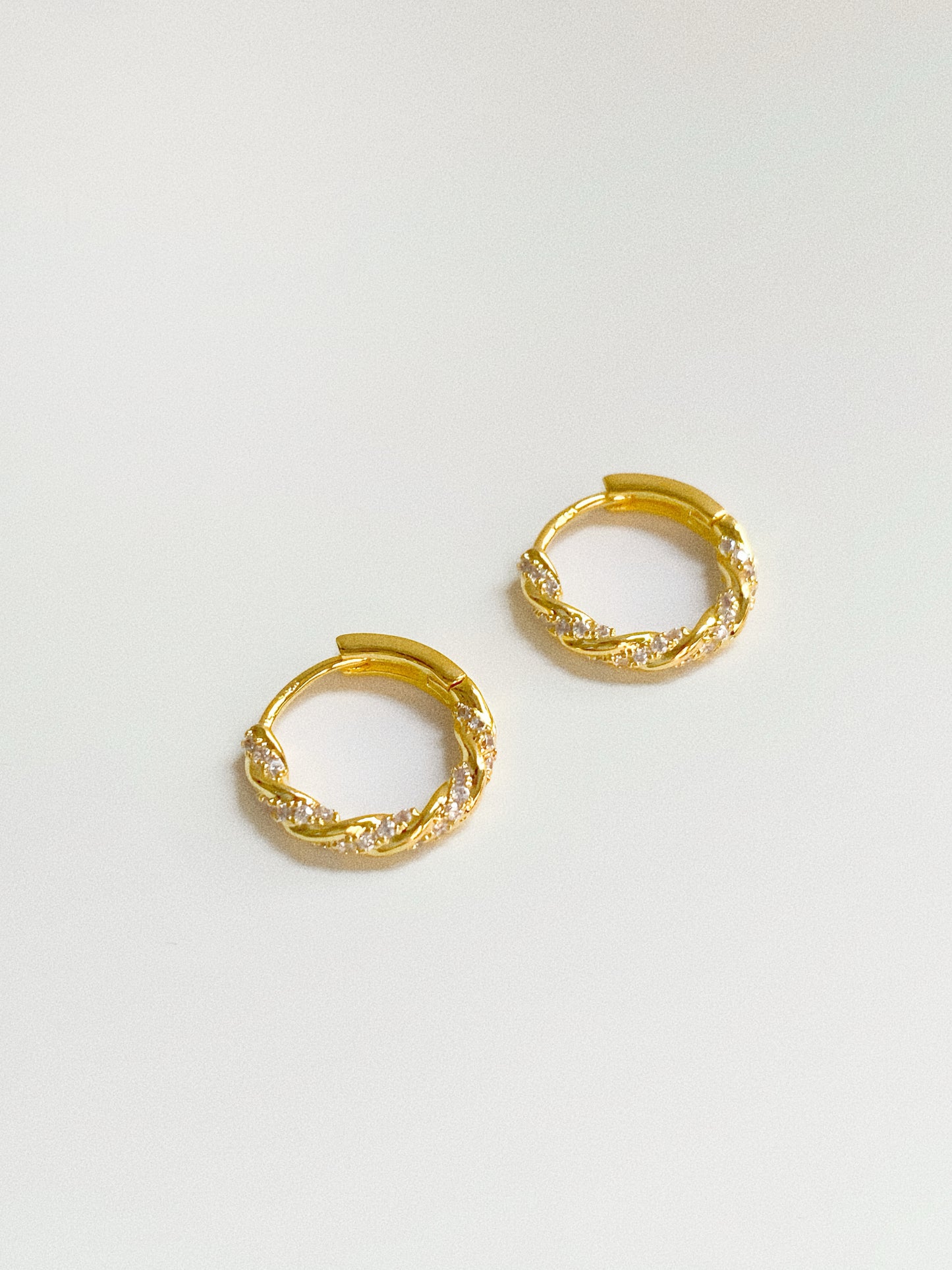 18k gold plated twisted huggie hoop earrings with pavé cubic zirconia, close-up detail shot