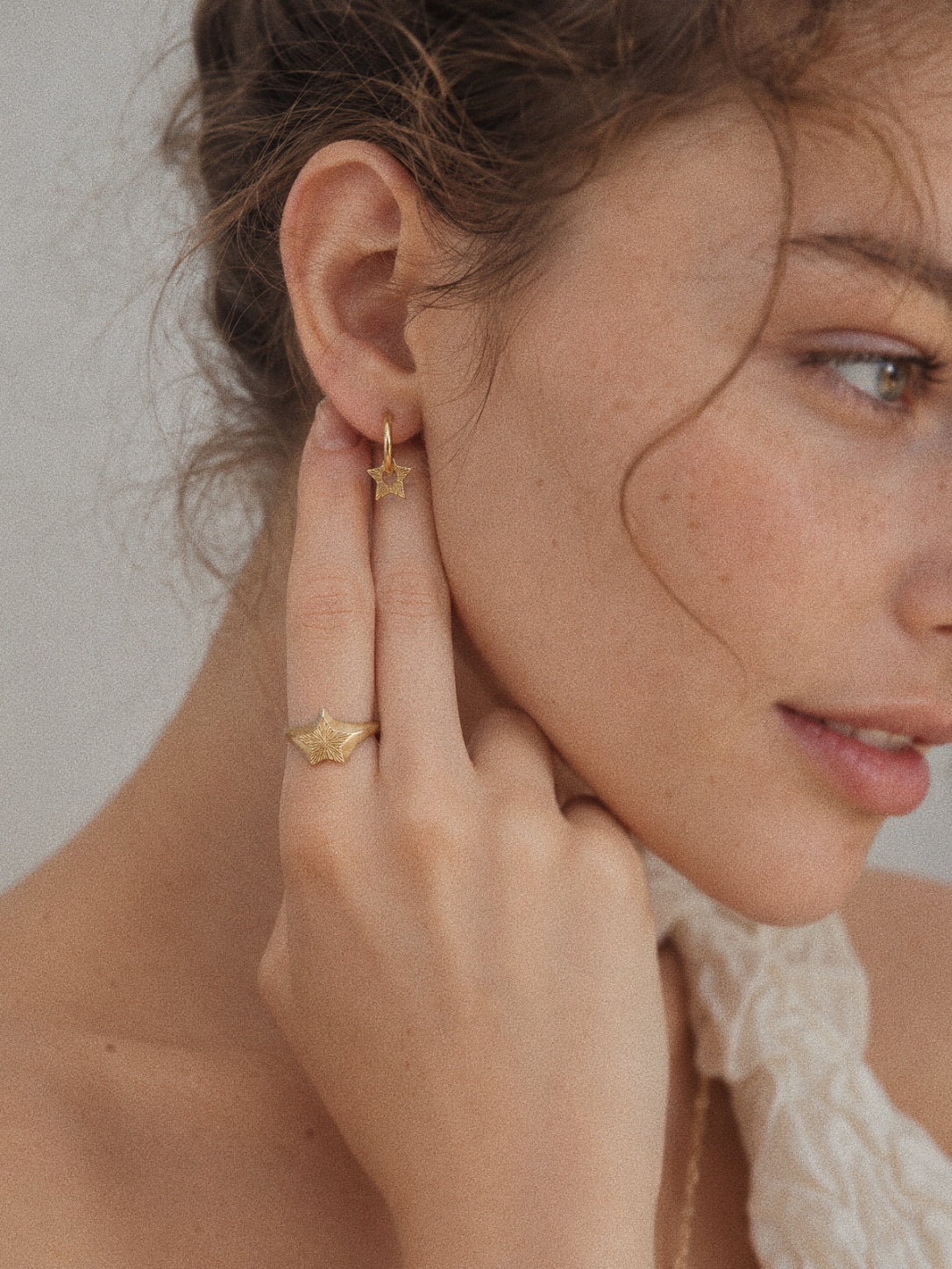 Gold Nova star huggie earring worn with the matching Nova star signet ring on the hand.