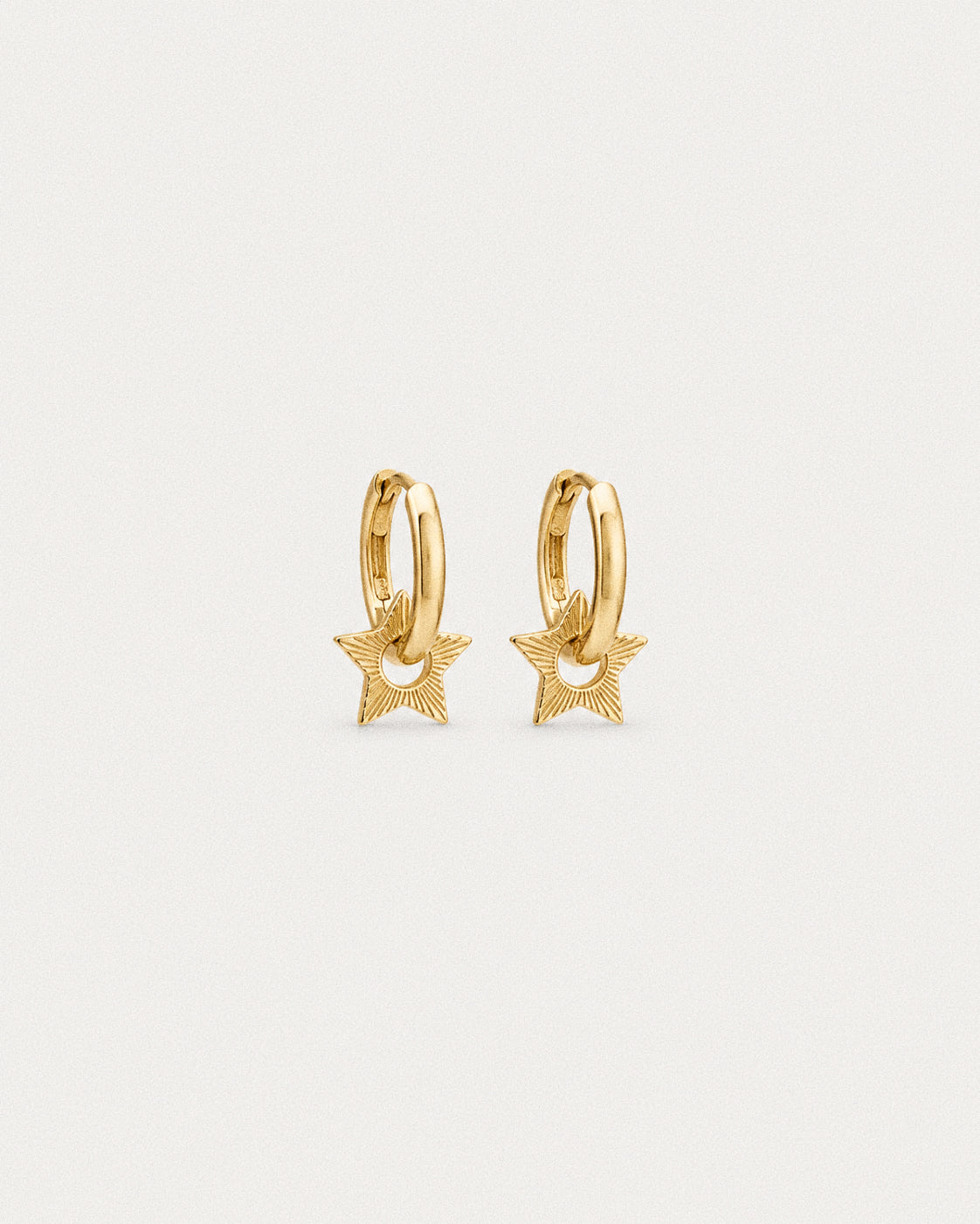 Gold plated star huggie hoop earrings, engraved rays radiating across each open centred star charm.